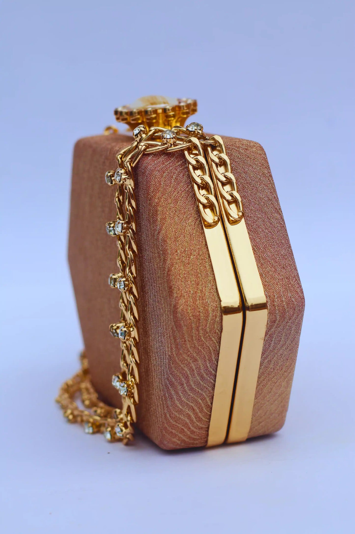 Brown handbag for bridewith gold chain and accents on a light blue background