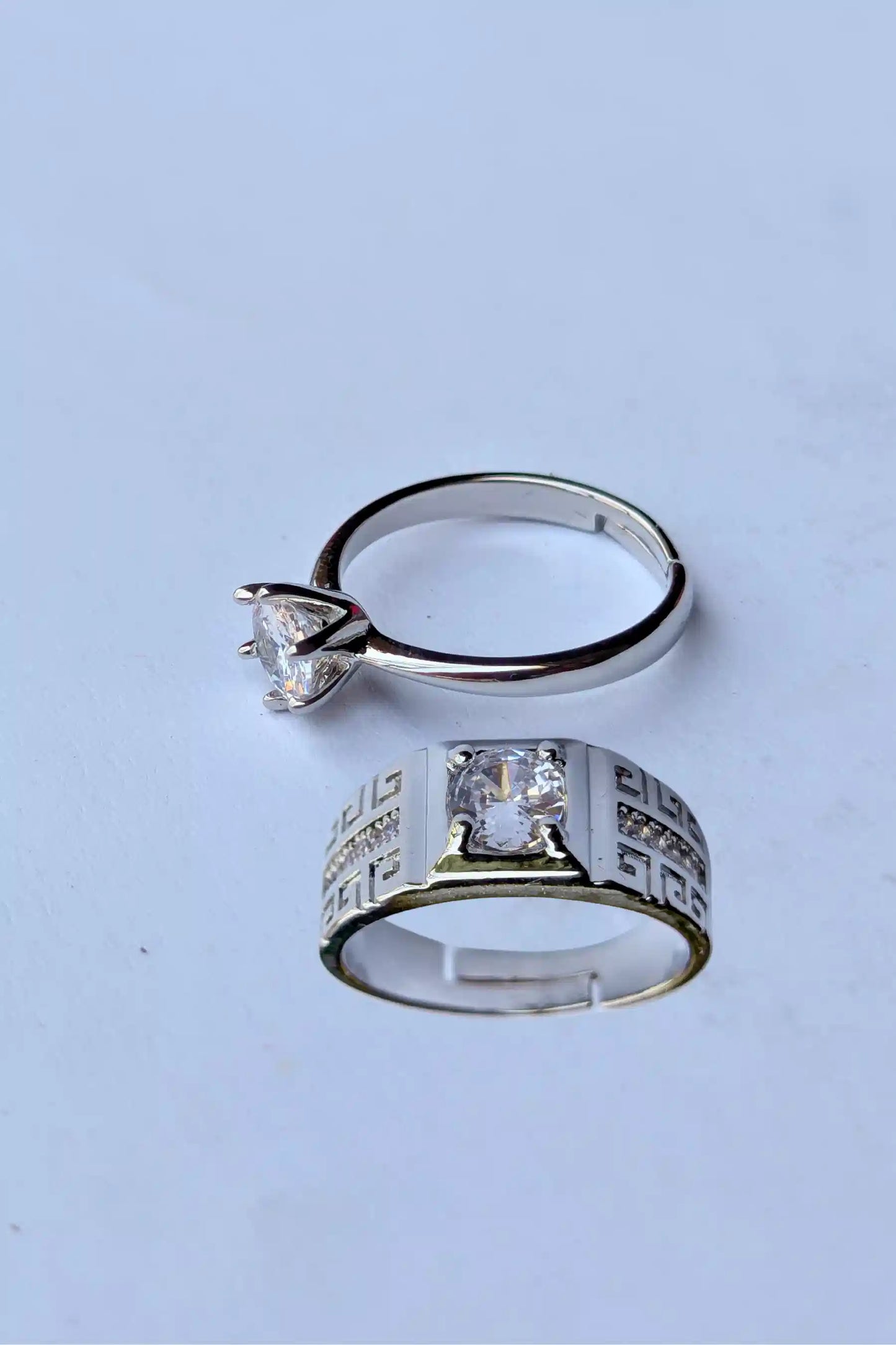Two silver rings with gemstones on a light blue background