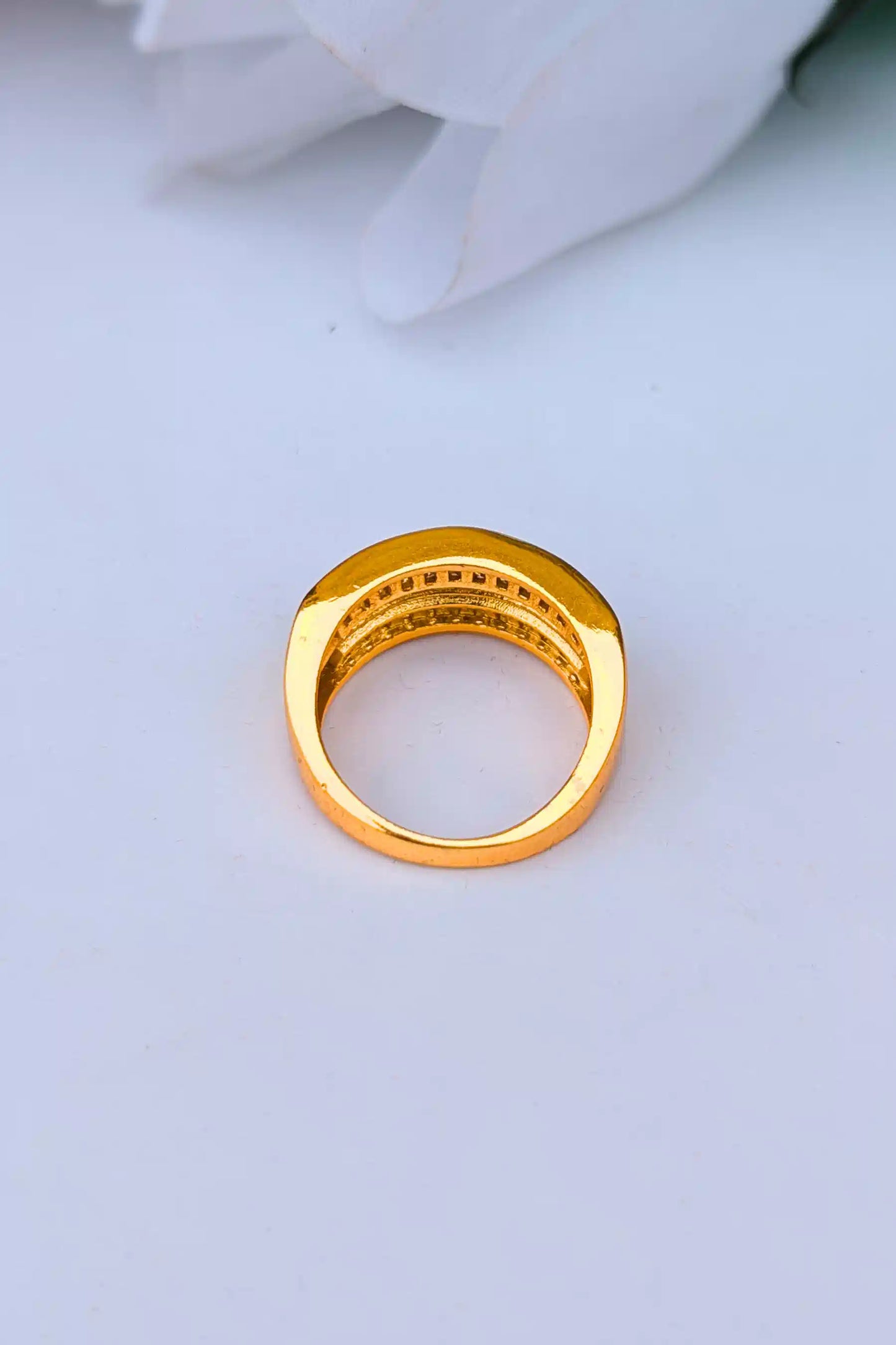 Gold ring with embedded stones on a light gray background