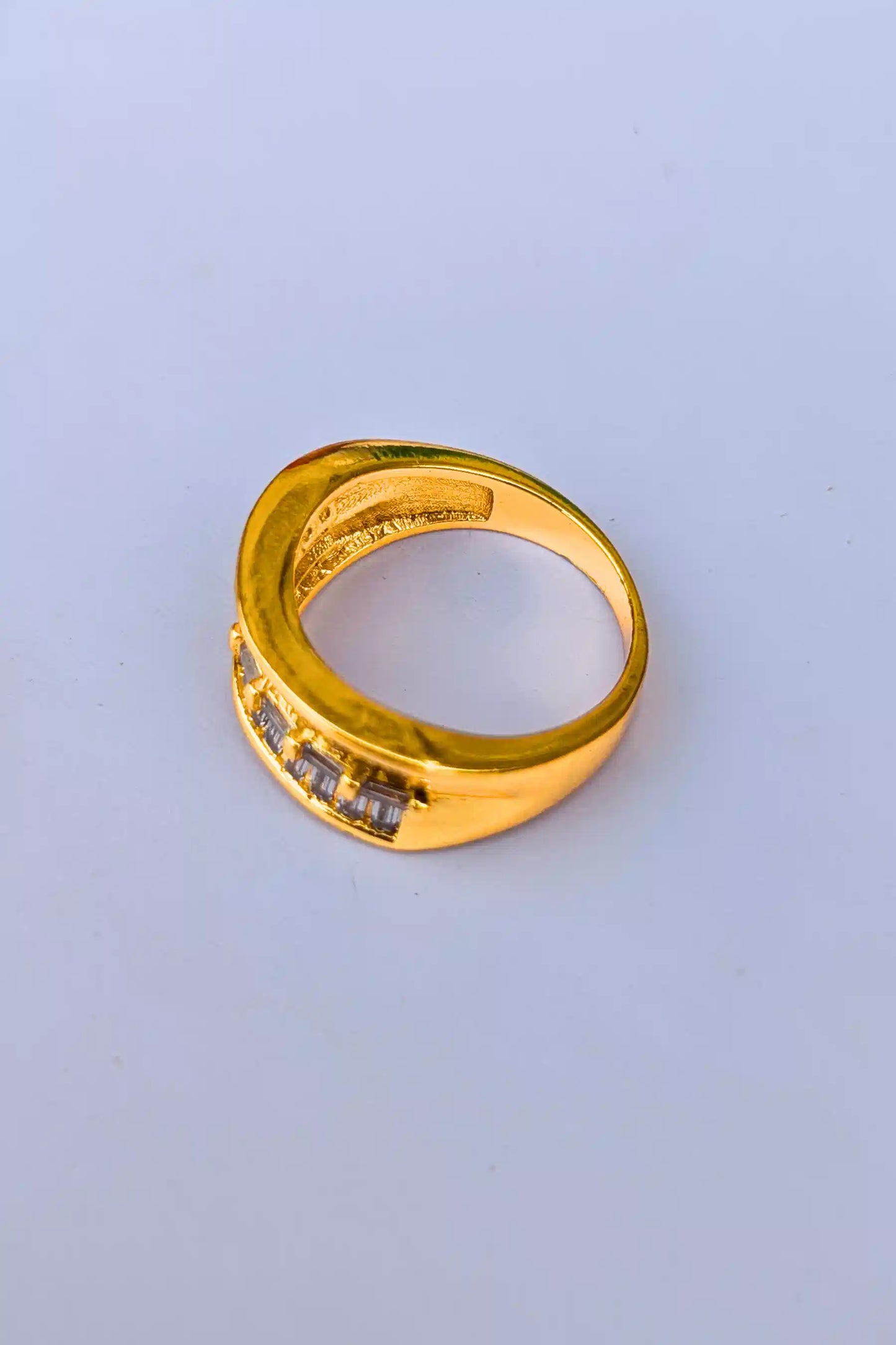 Gold ring with embedded stones on a light blue background