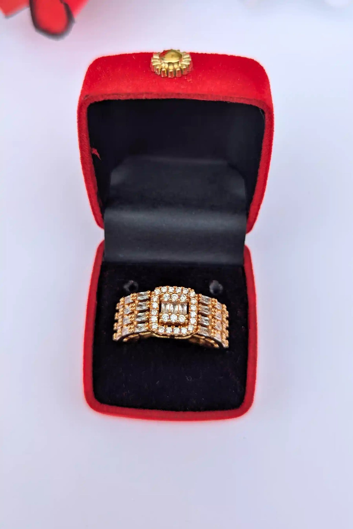 Gold ring with diamond accents in a red jewelry box on a white background