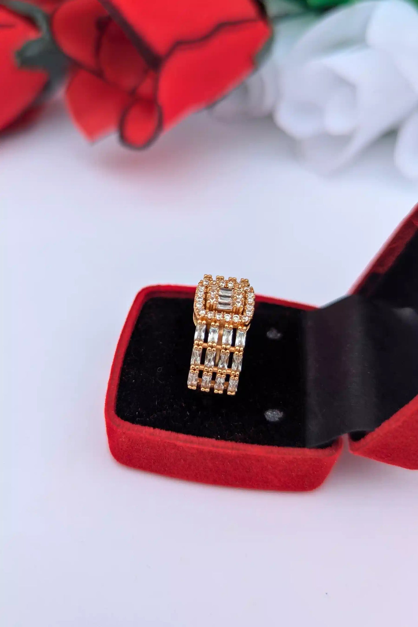 Gold ring with diamonds in a red jewelry box on a white background