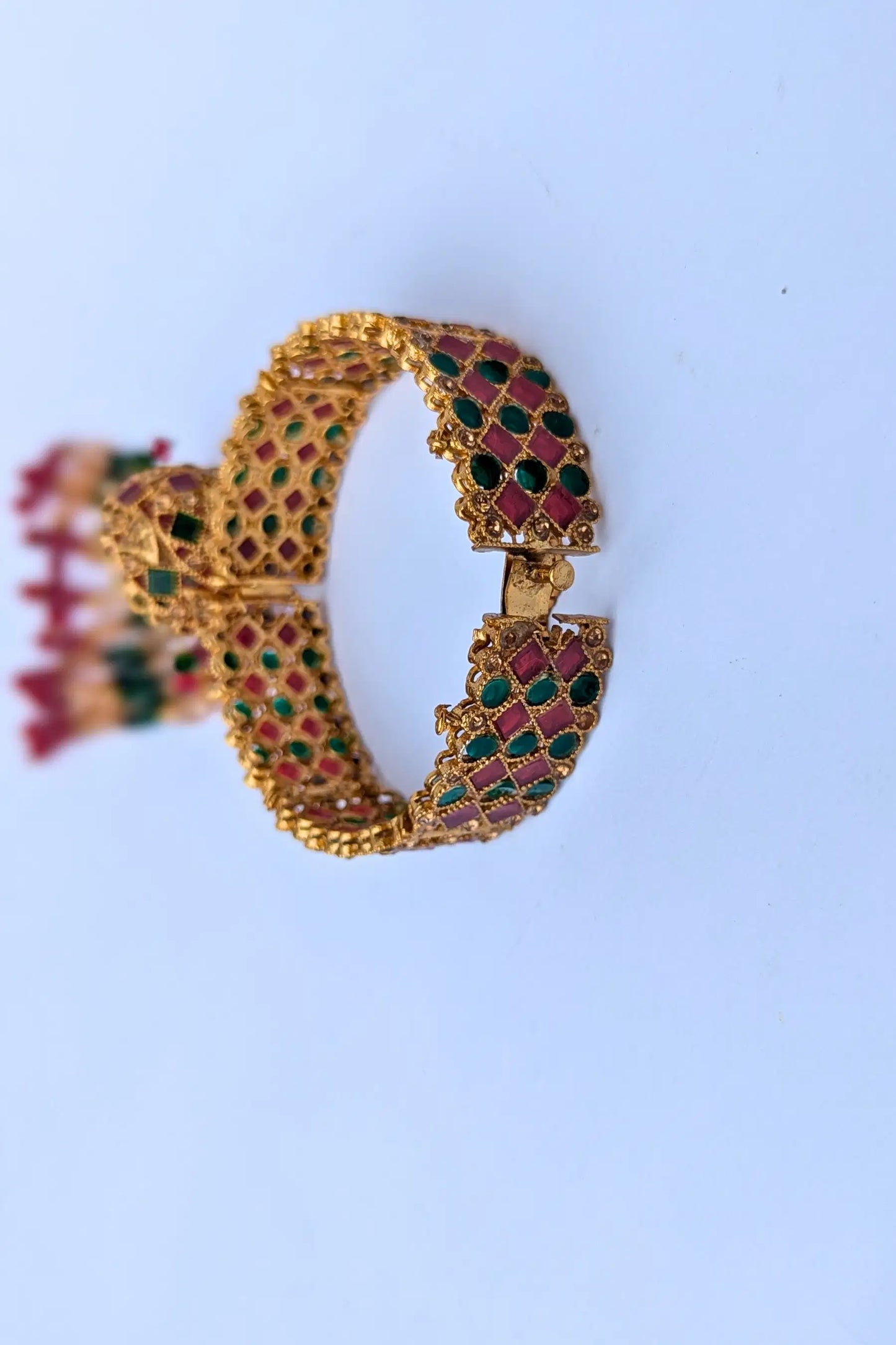 Gold bracelet with gemstones on a light blue background