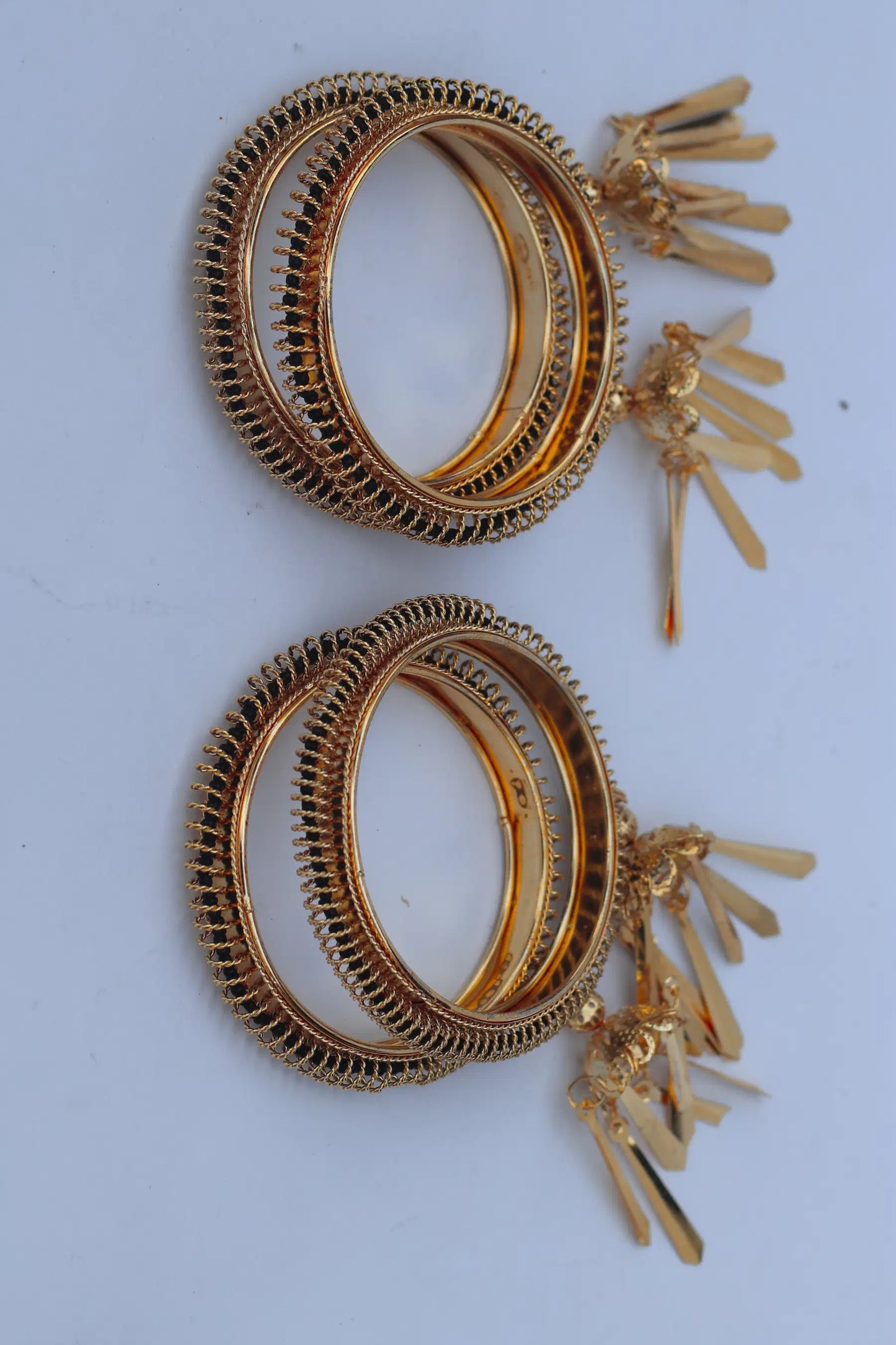 2 Pair of gold hoop earrings with tassel details on a light gray background