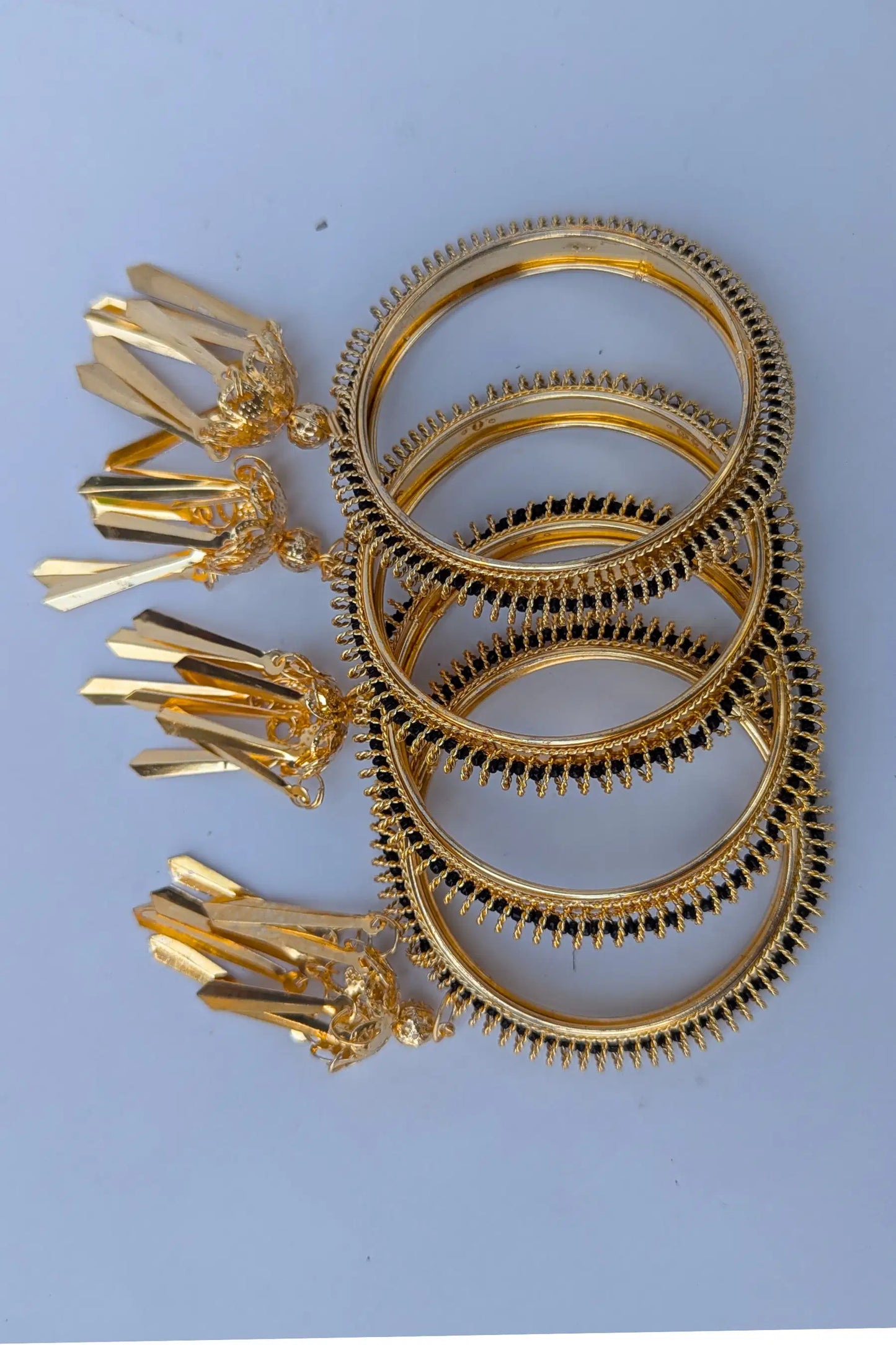 Set of gold bangles with decorative ends on a light blue background
