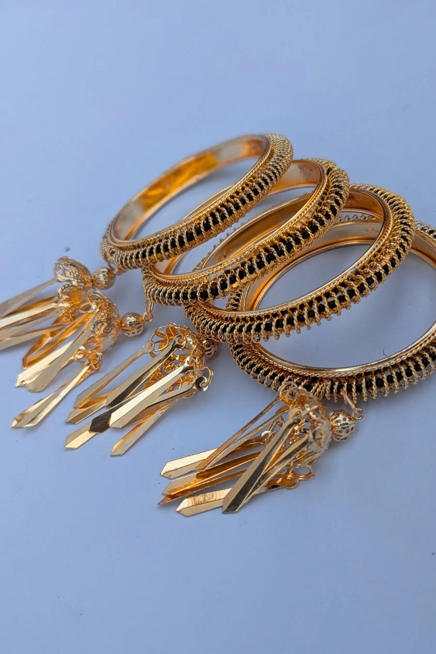 Gold bangles with decorative elements on a blue background