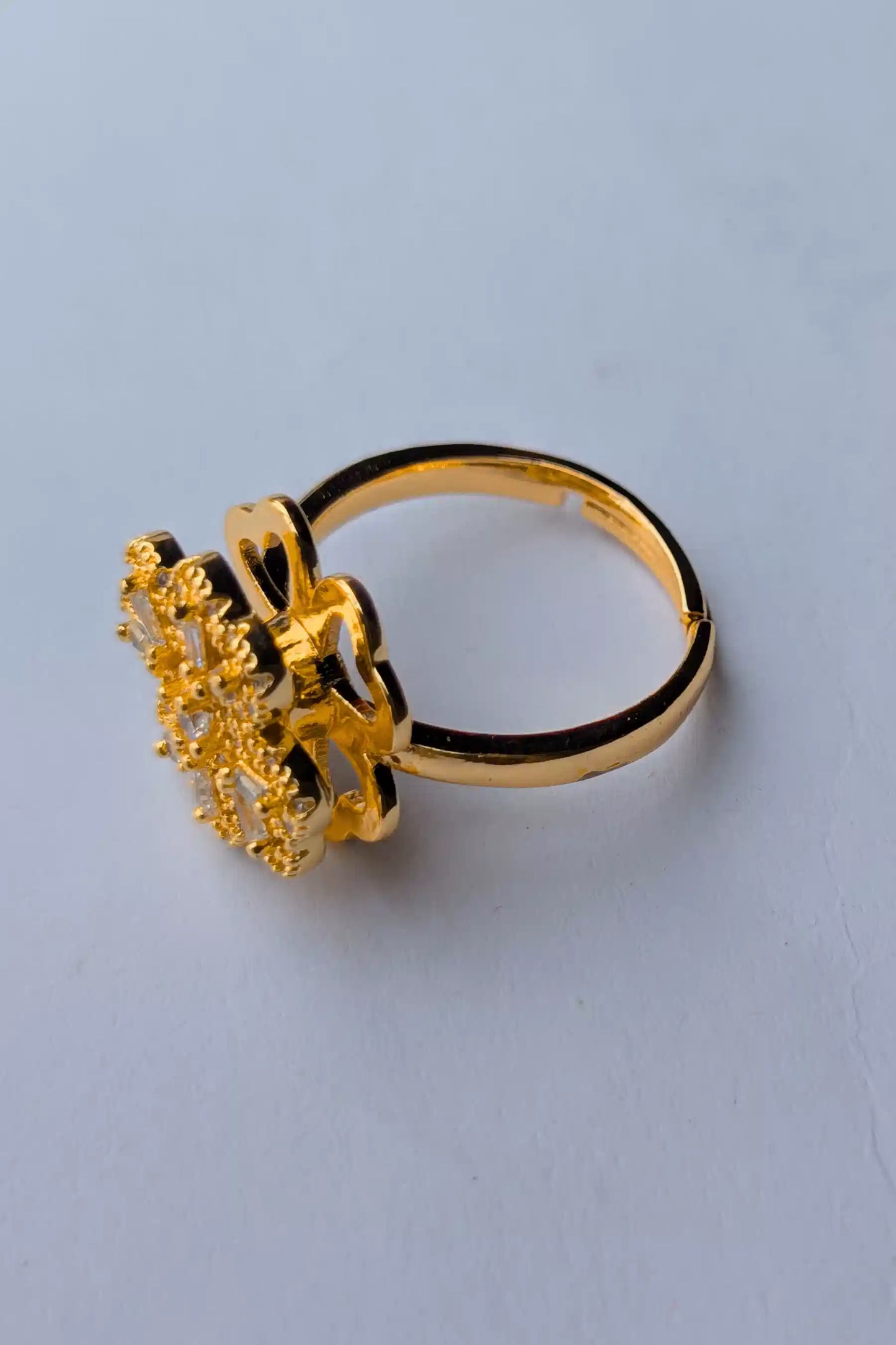 Gold ring with intricate design on a light blue background