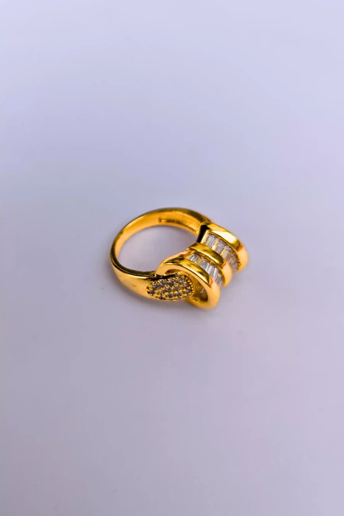 Gold ring with gemstones on a light gray background