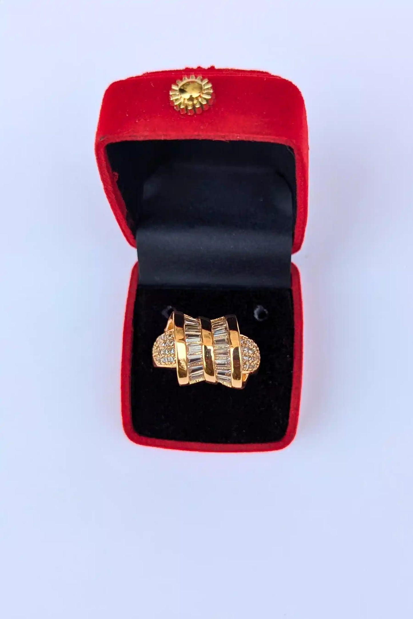 Gold ring in a red velvet box on a white background