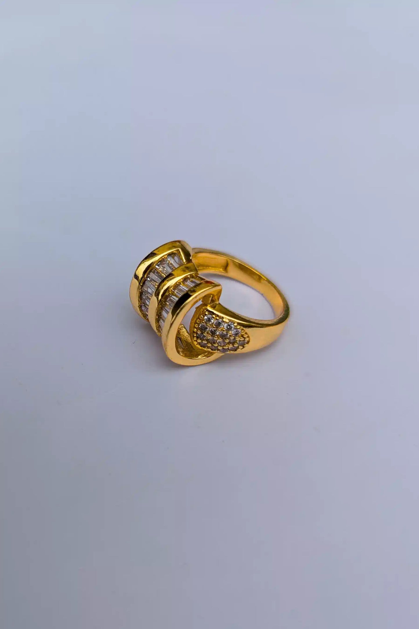 Gold ring with embedded stones on a light gray background