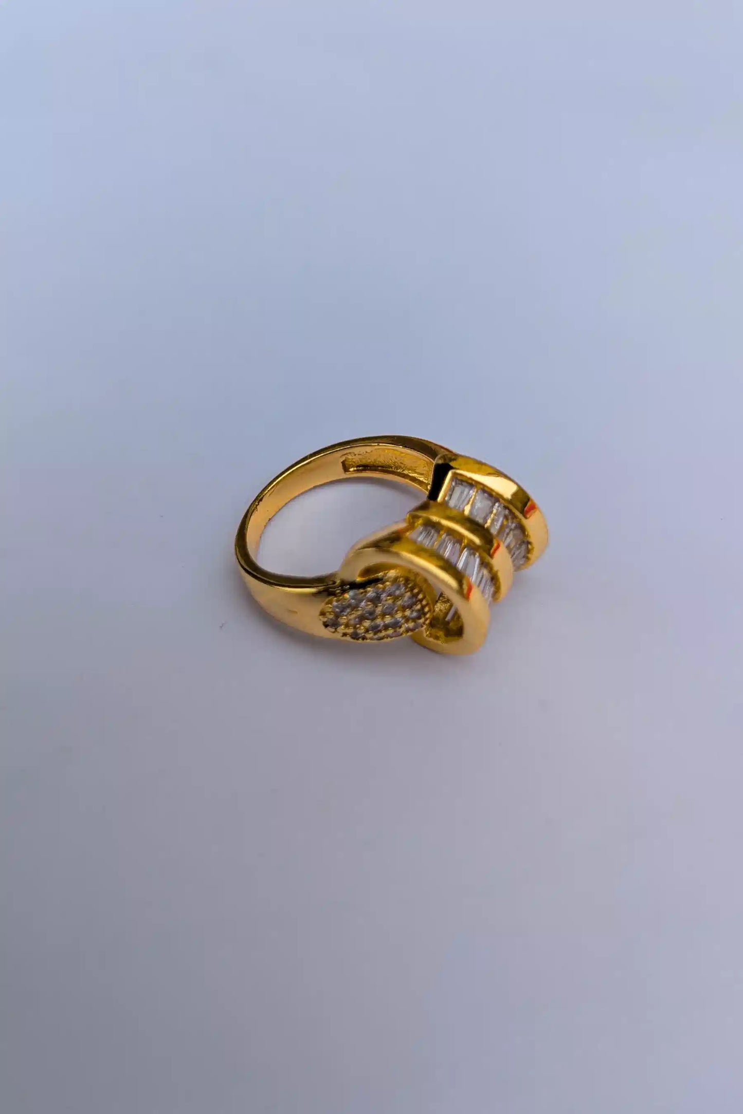 Gold ring with embedded stones on a light gray background