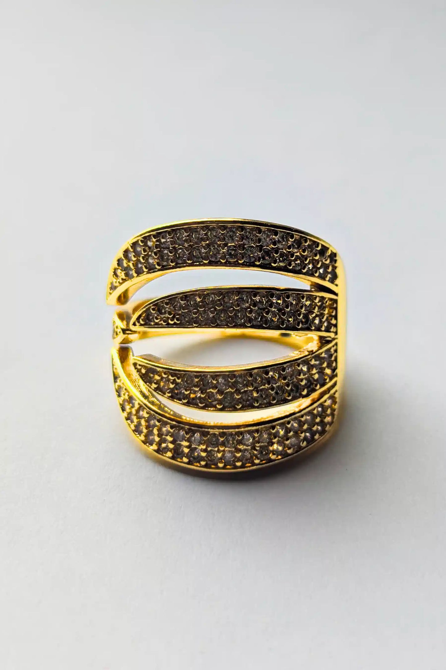 Gold ring with black gemstones on a light gray background