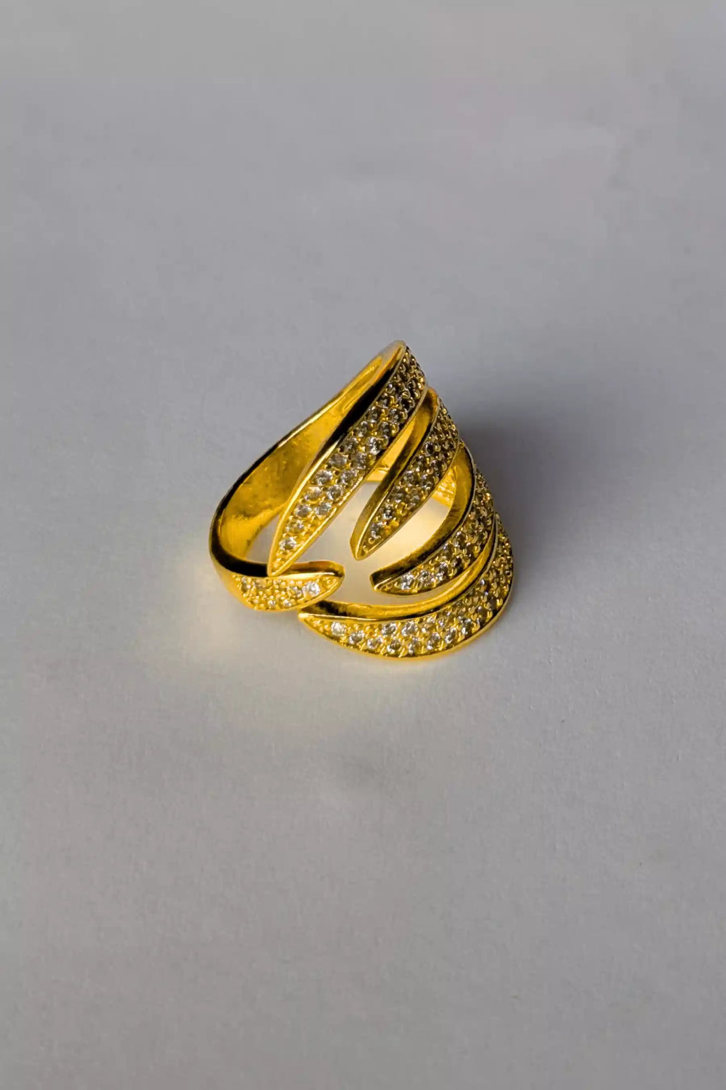 Gold ring with intricate design on a gray background