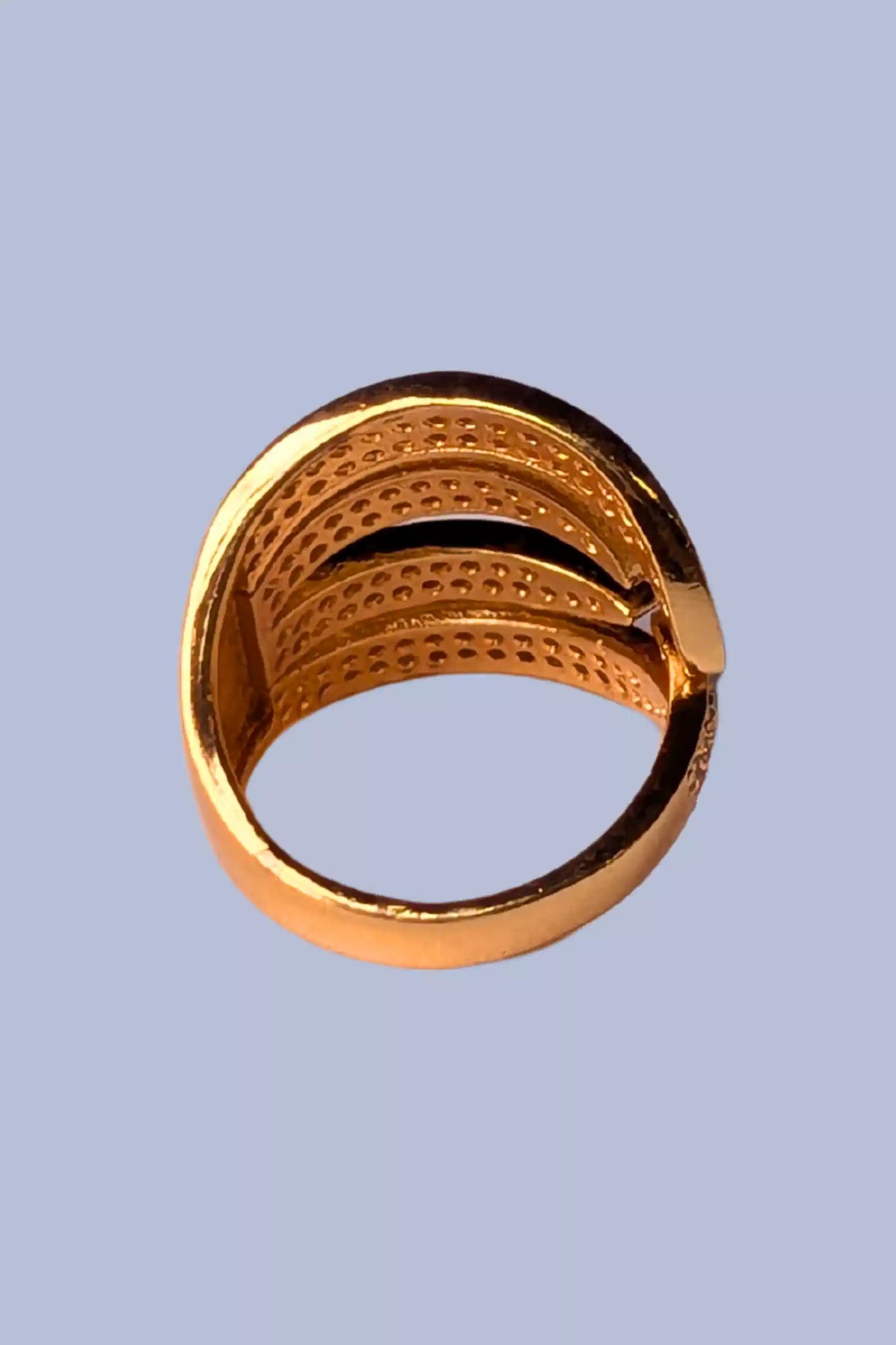 Gold ring with textured design on a light blue background