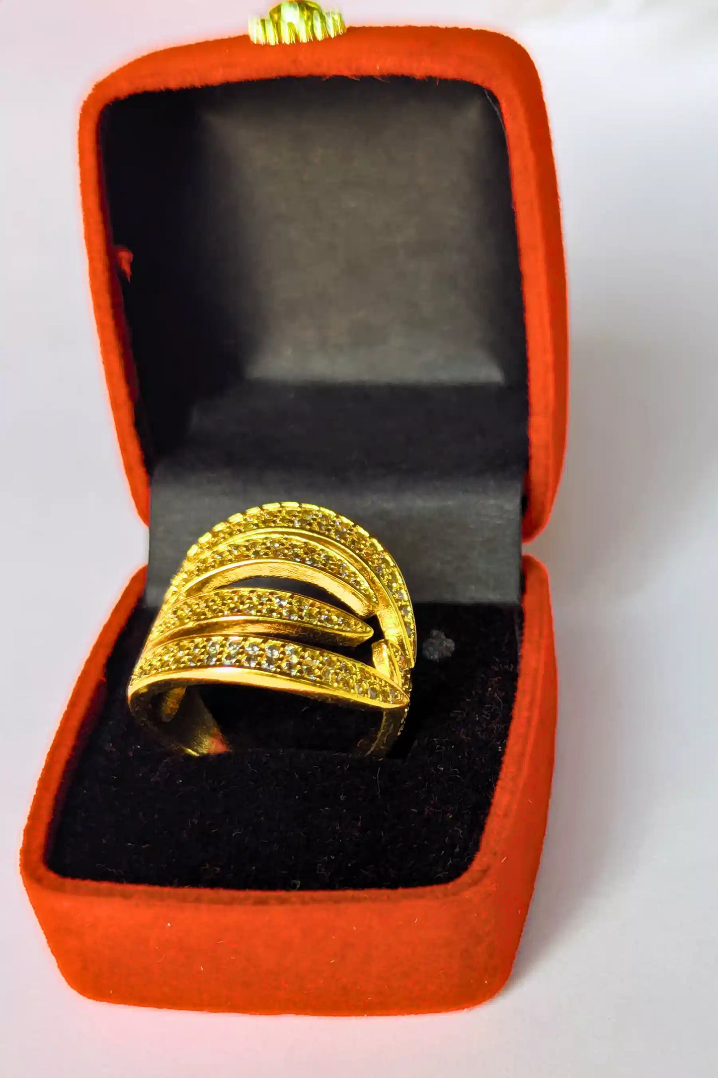 Gold ring in an open red jewelry box on a white background