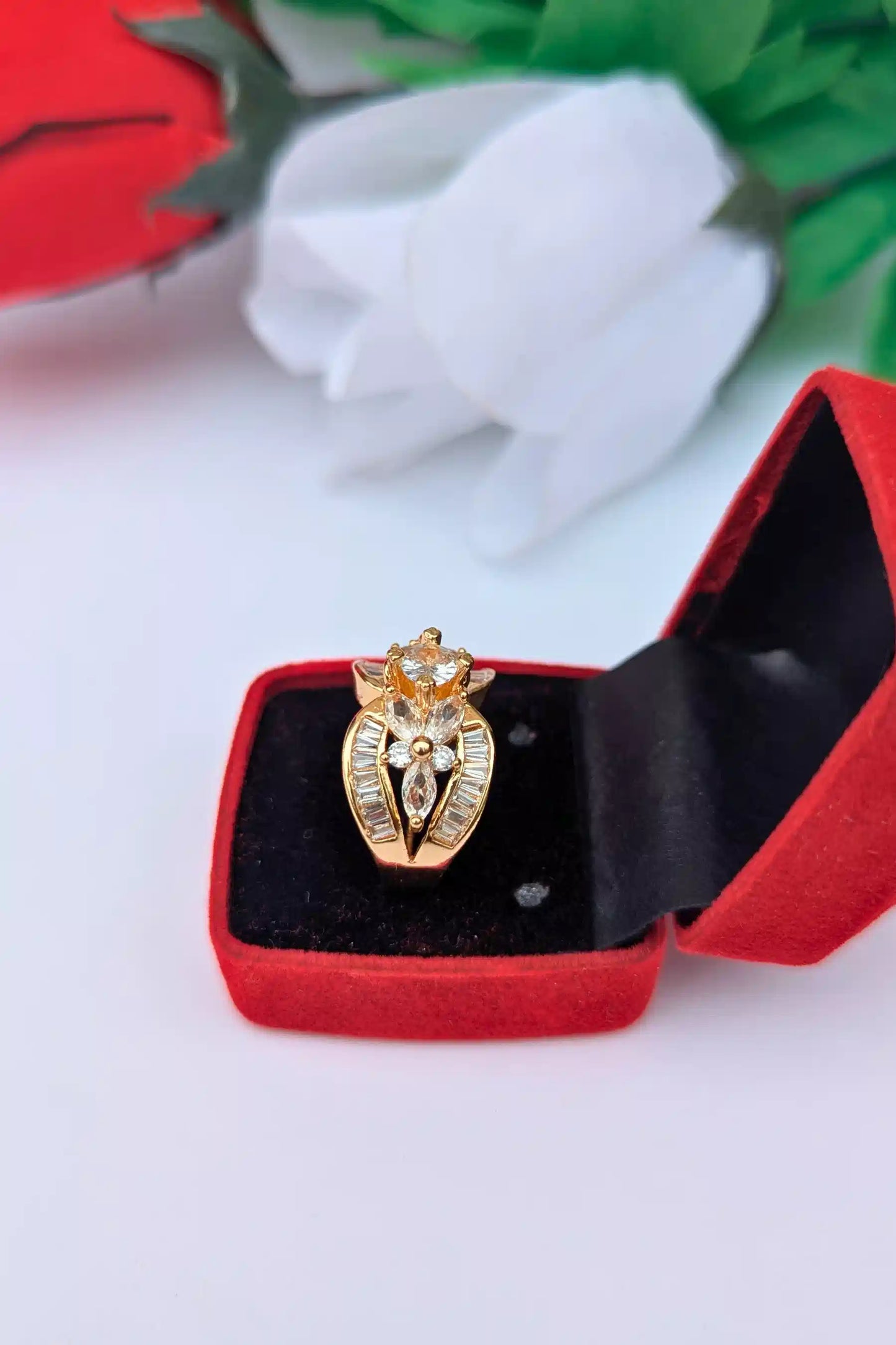 Gold ring with gemstones in a red jewelry box on a white background