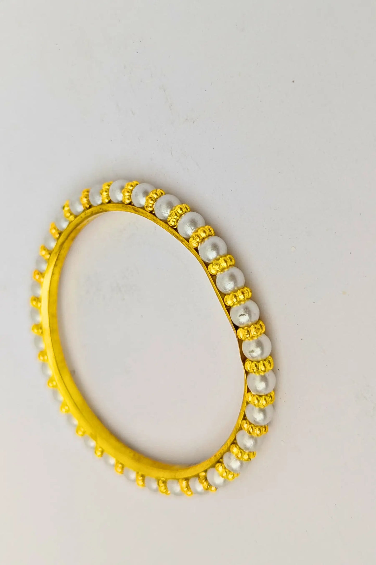 Gold and pearl bracelet on a light gray background