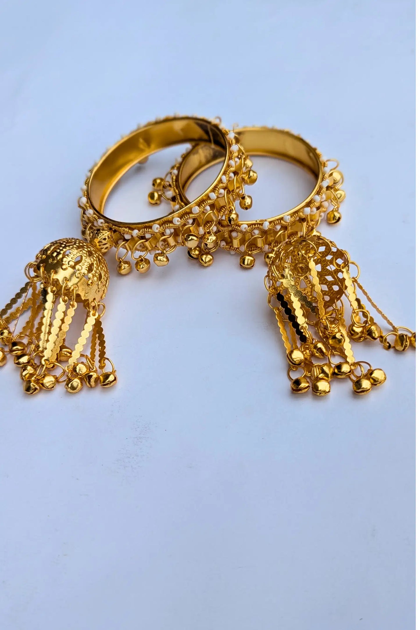 Gold bangles with decorative elements on a light blue background