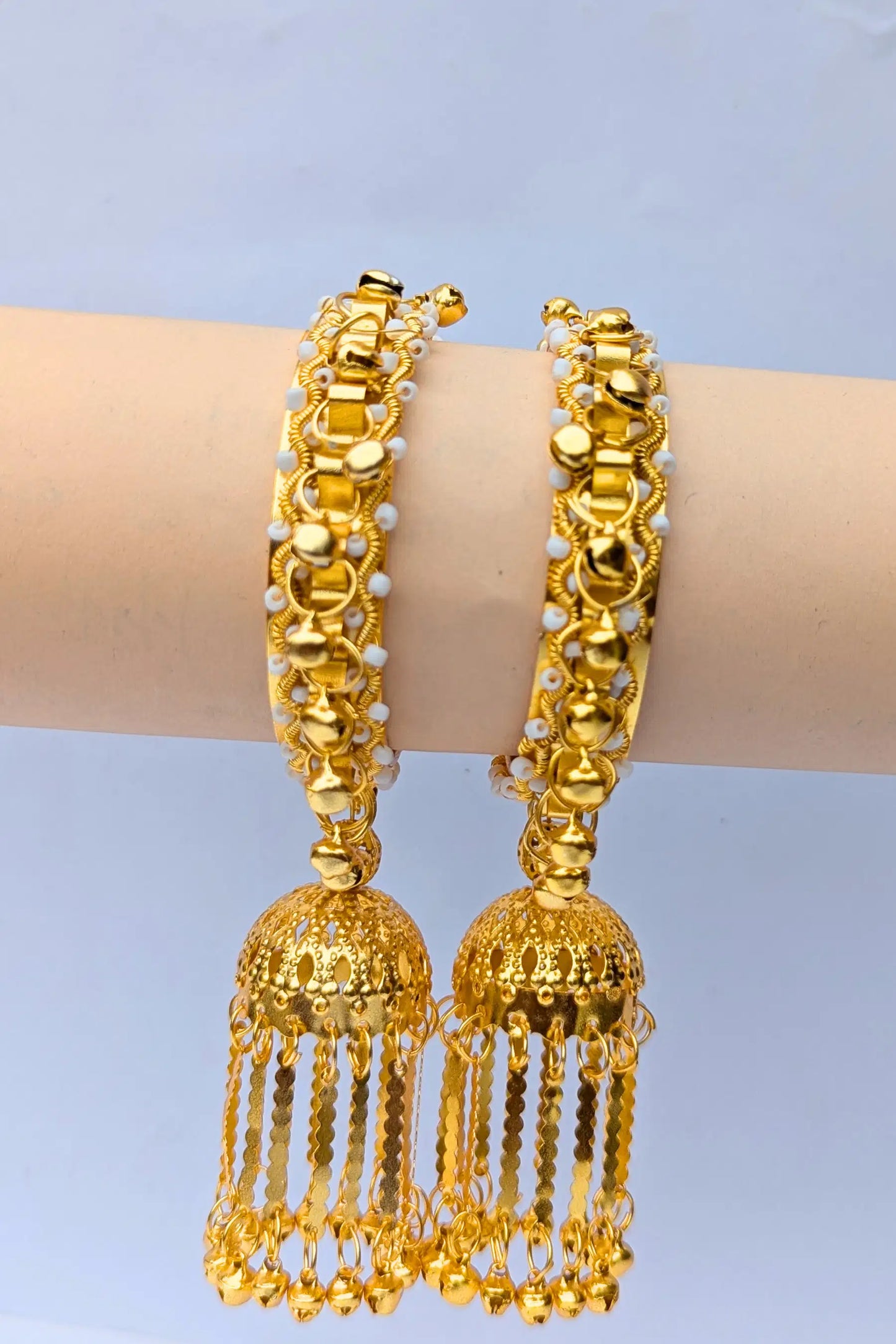 Gold bangles with tassels on a light blue background