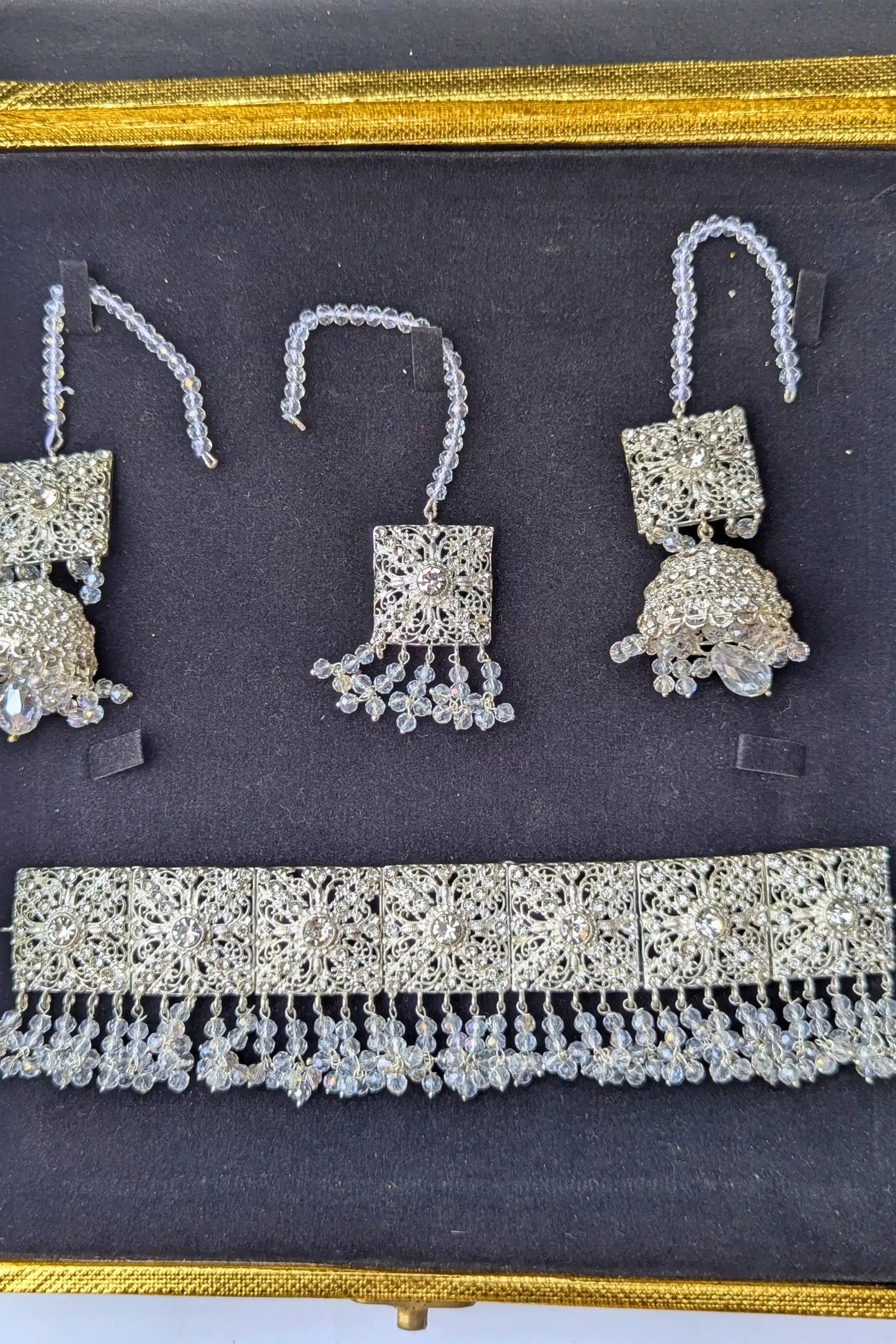 Set of silver jewelry including earrings and a necklace on a dark background