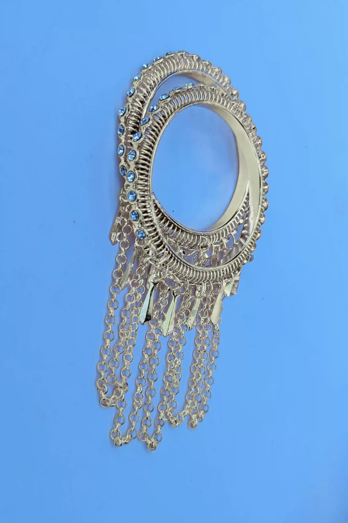 Decorative silver brooch with chains on a blue background