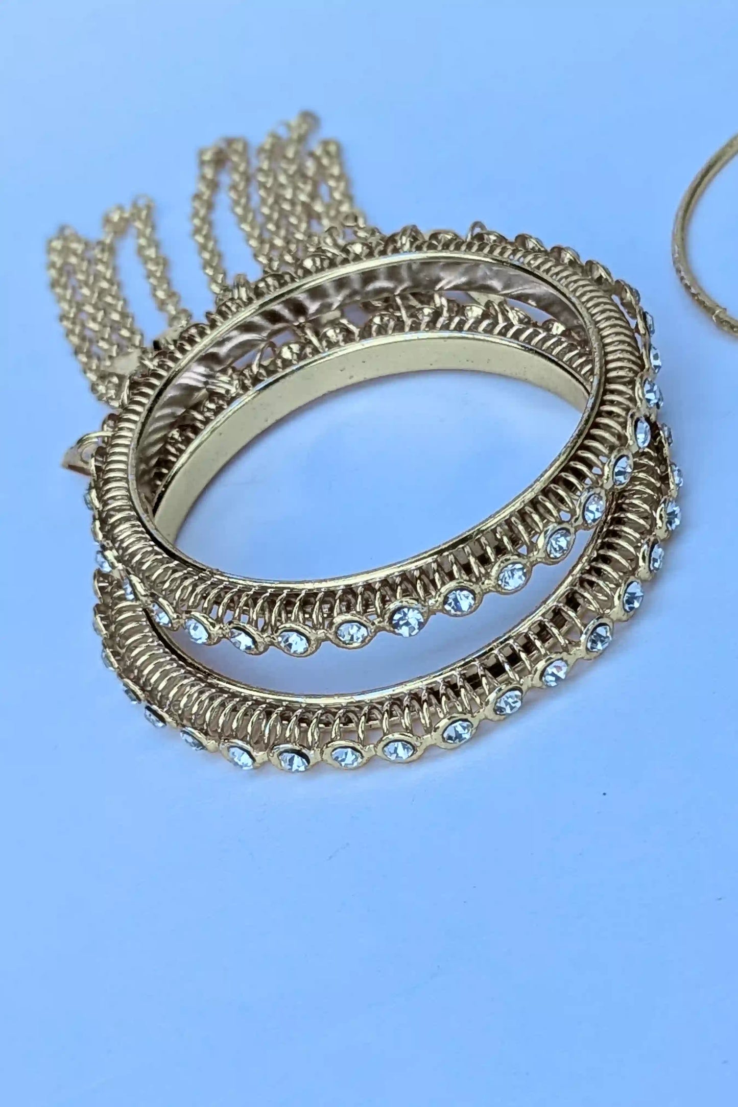 Gold bangles with gemstones on a light blue background
