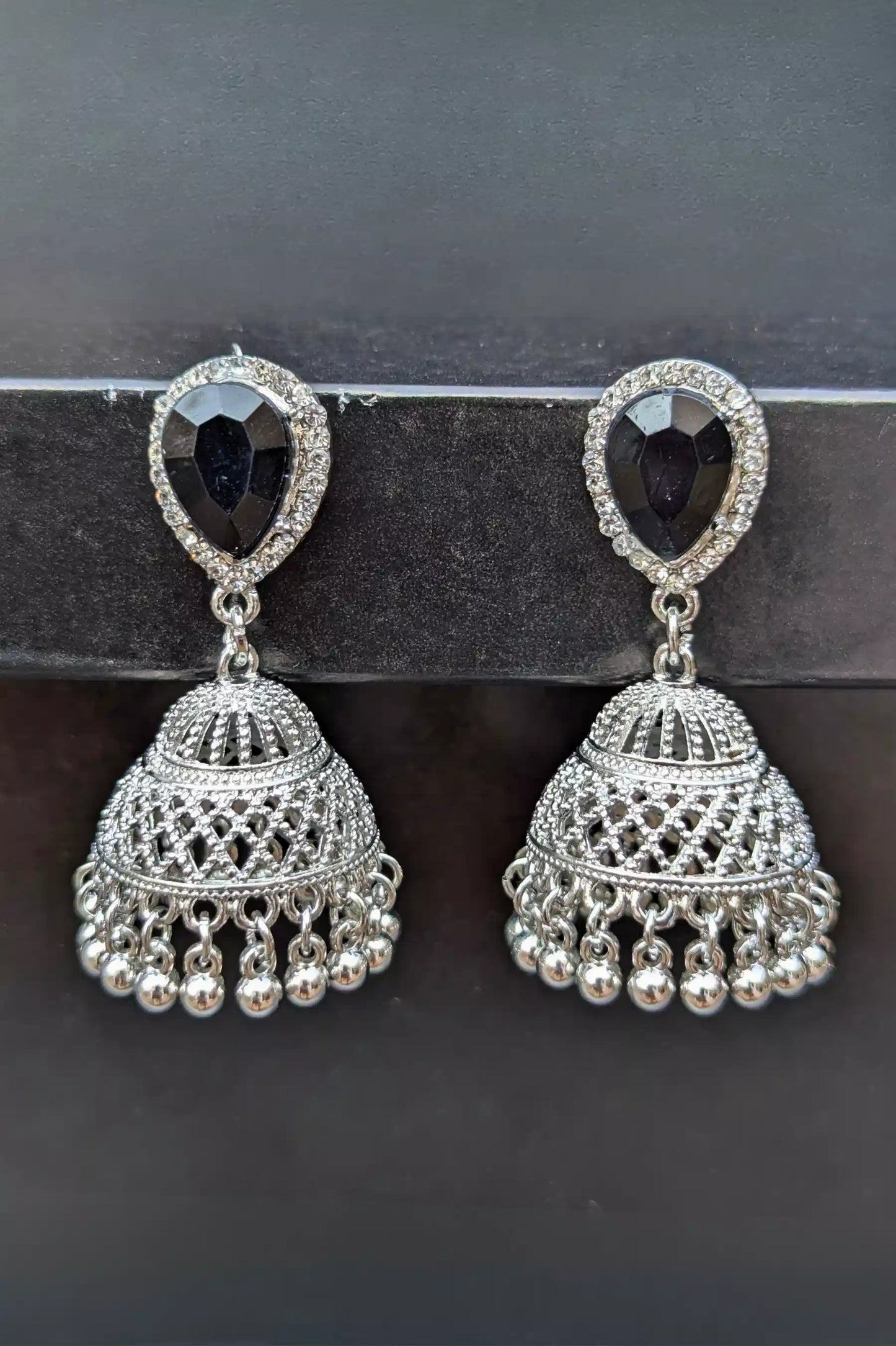 Pair of silver earrings with black gemstones on a dark background
