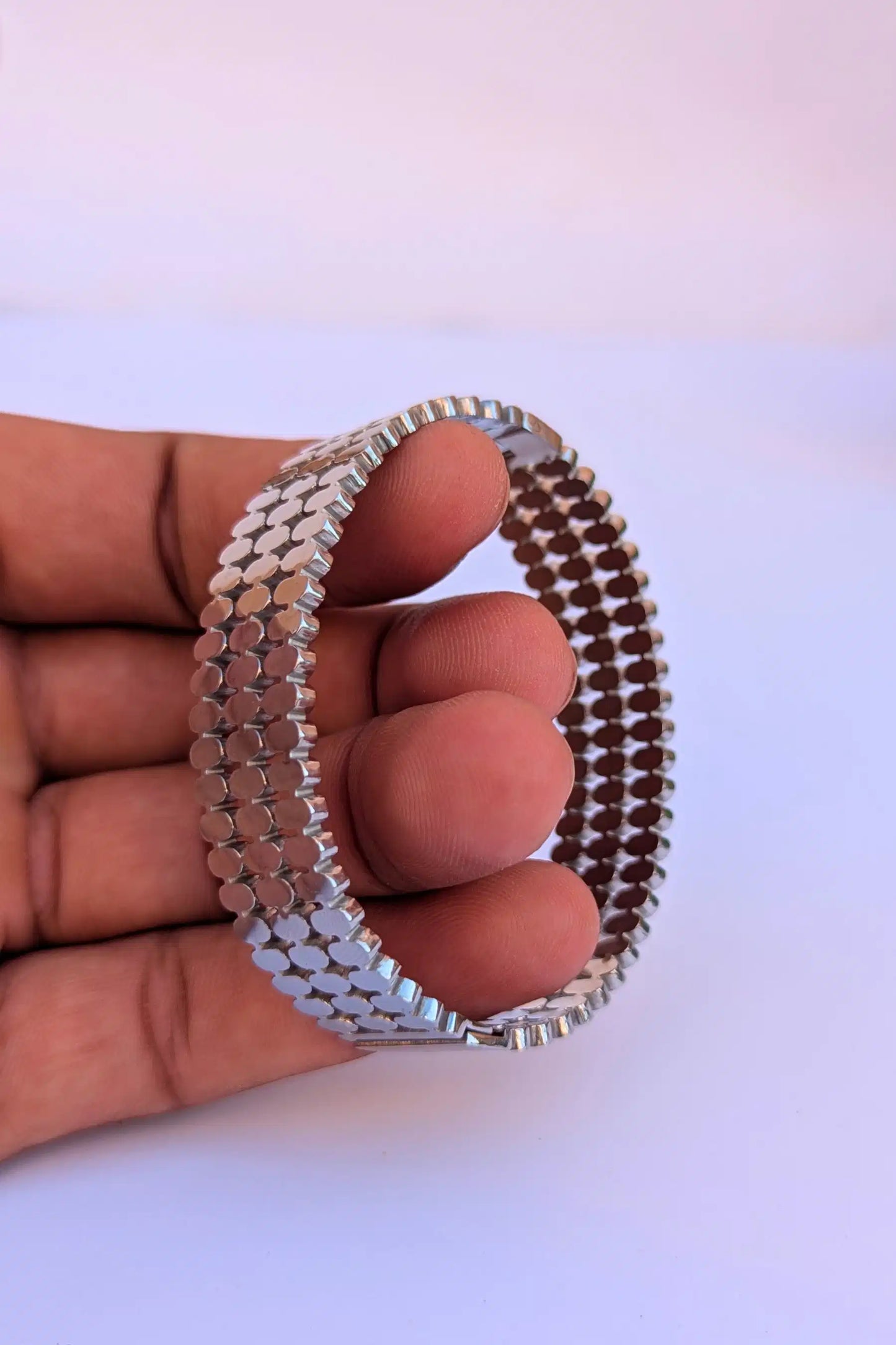 Silver beaded bracelet held by a hand on a white background