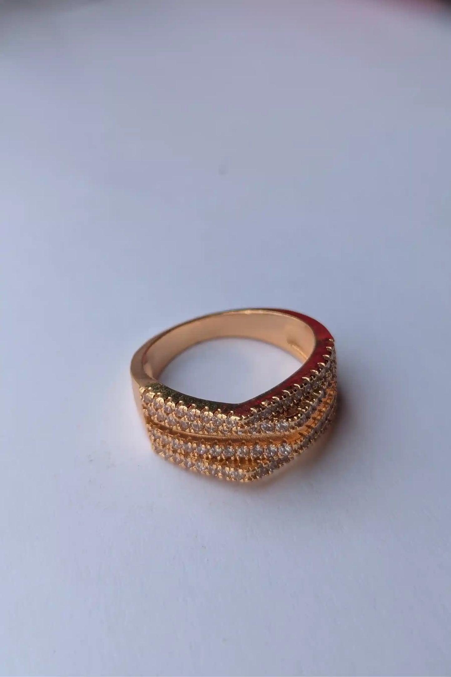 Gold ring with multiple bands on a light gray background