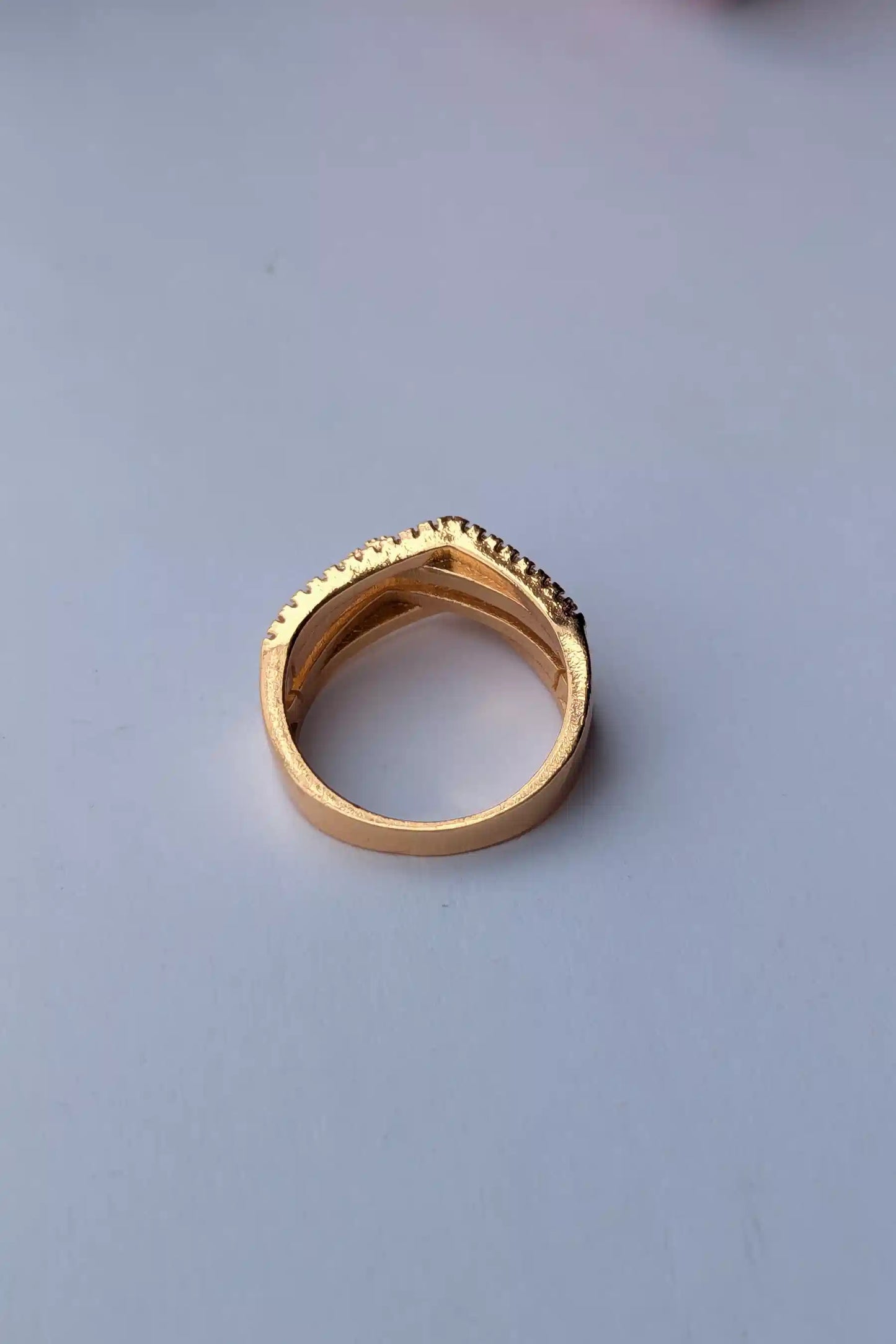 Gold ring with textured band on a light gray background