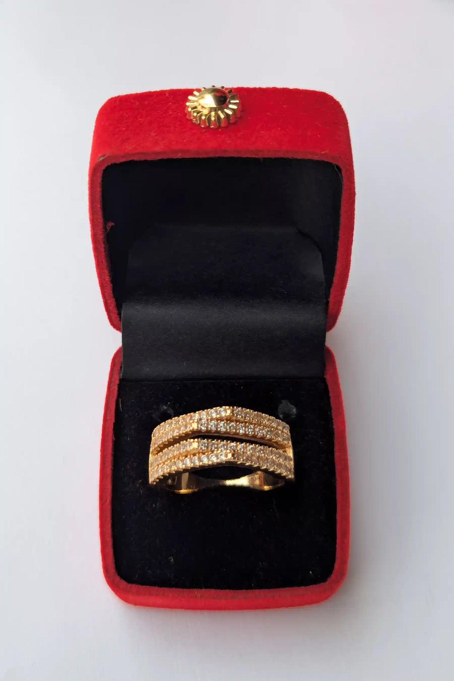 Gold ring in a red jewelry box on a white background