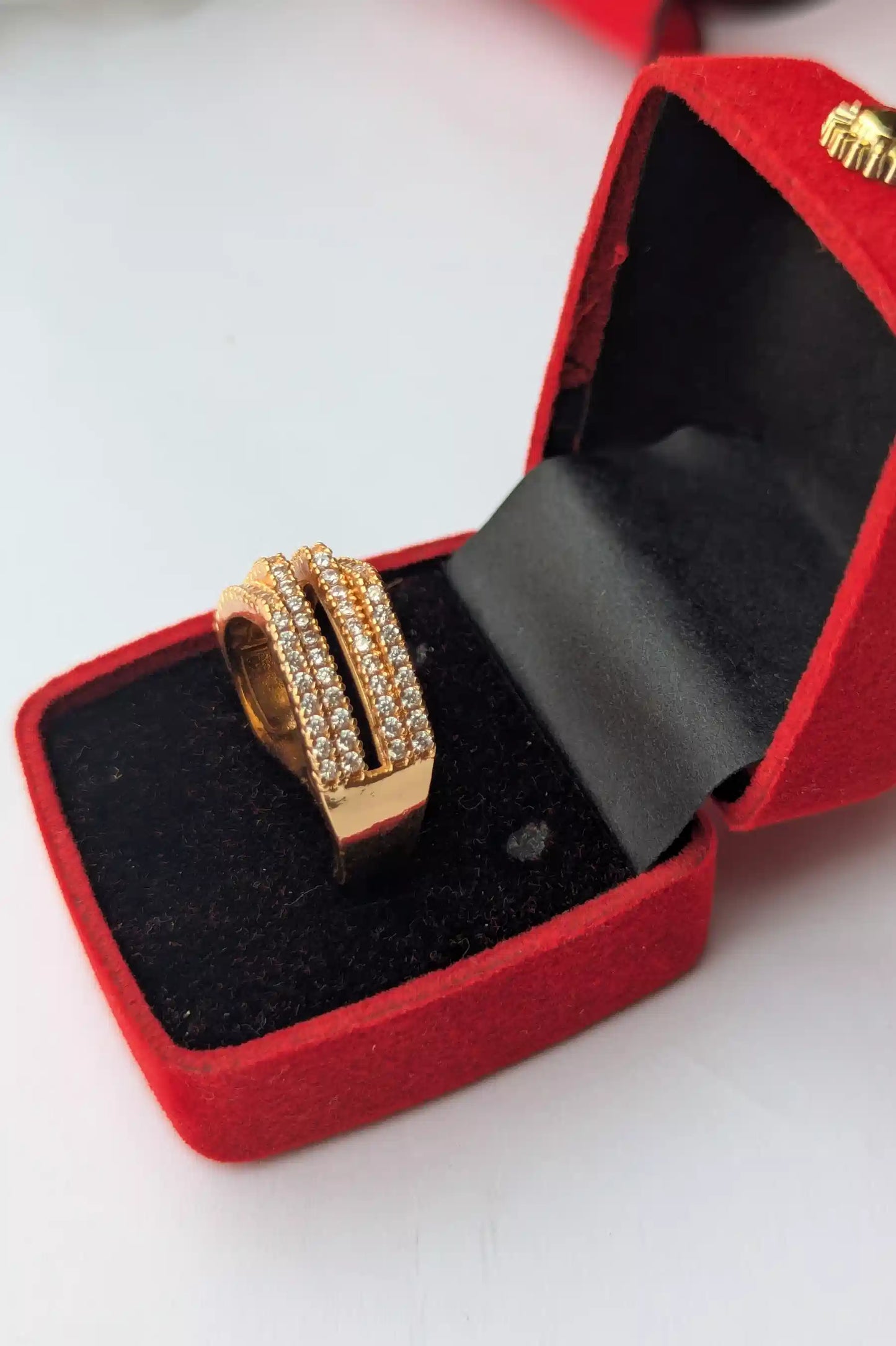 Gold ring with diamonds in a red jewelry box on a white background