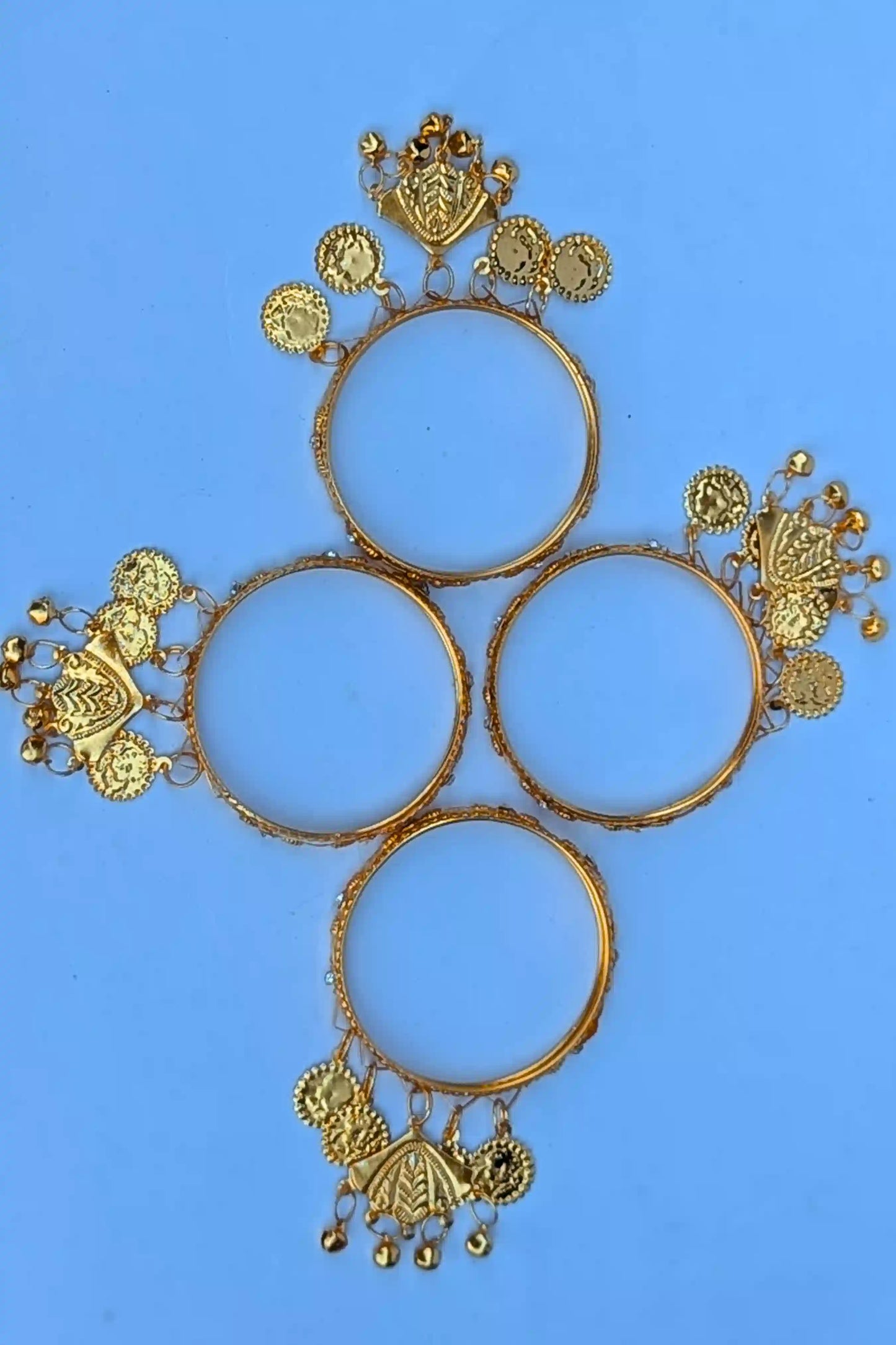 Set of gold bangles with intricate designs on a blue background