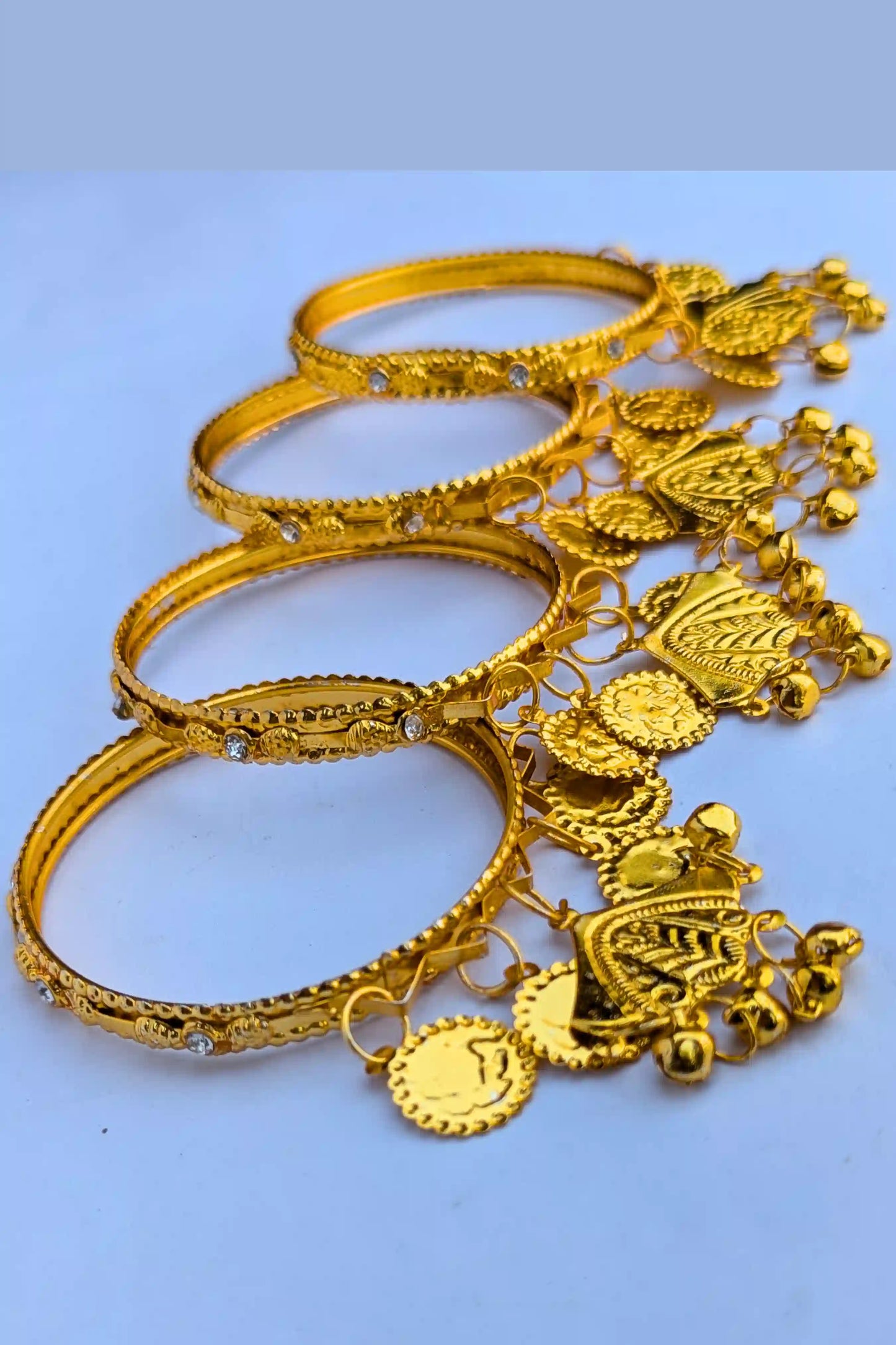 Set of gold bangles with intricate designs and charms top view