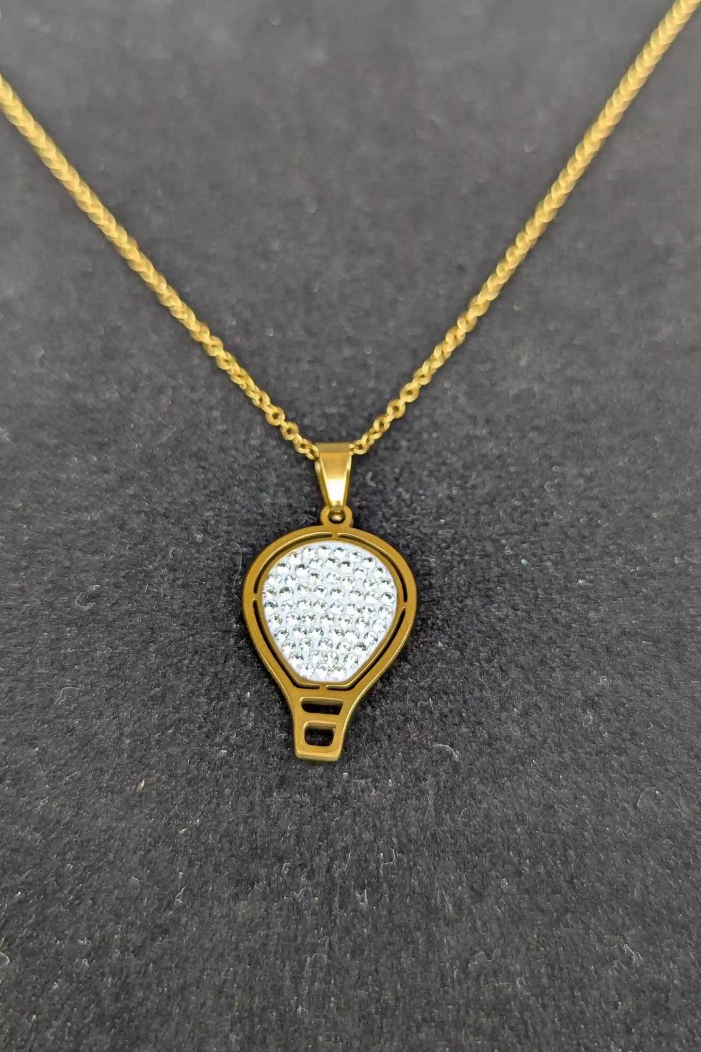 Gold necklace with a hot air balloon pendant on a gray background