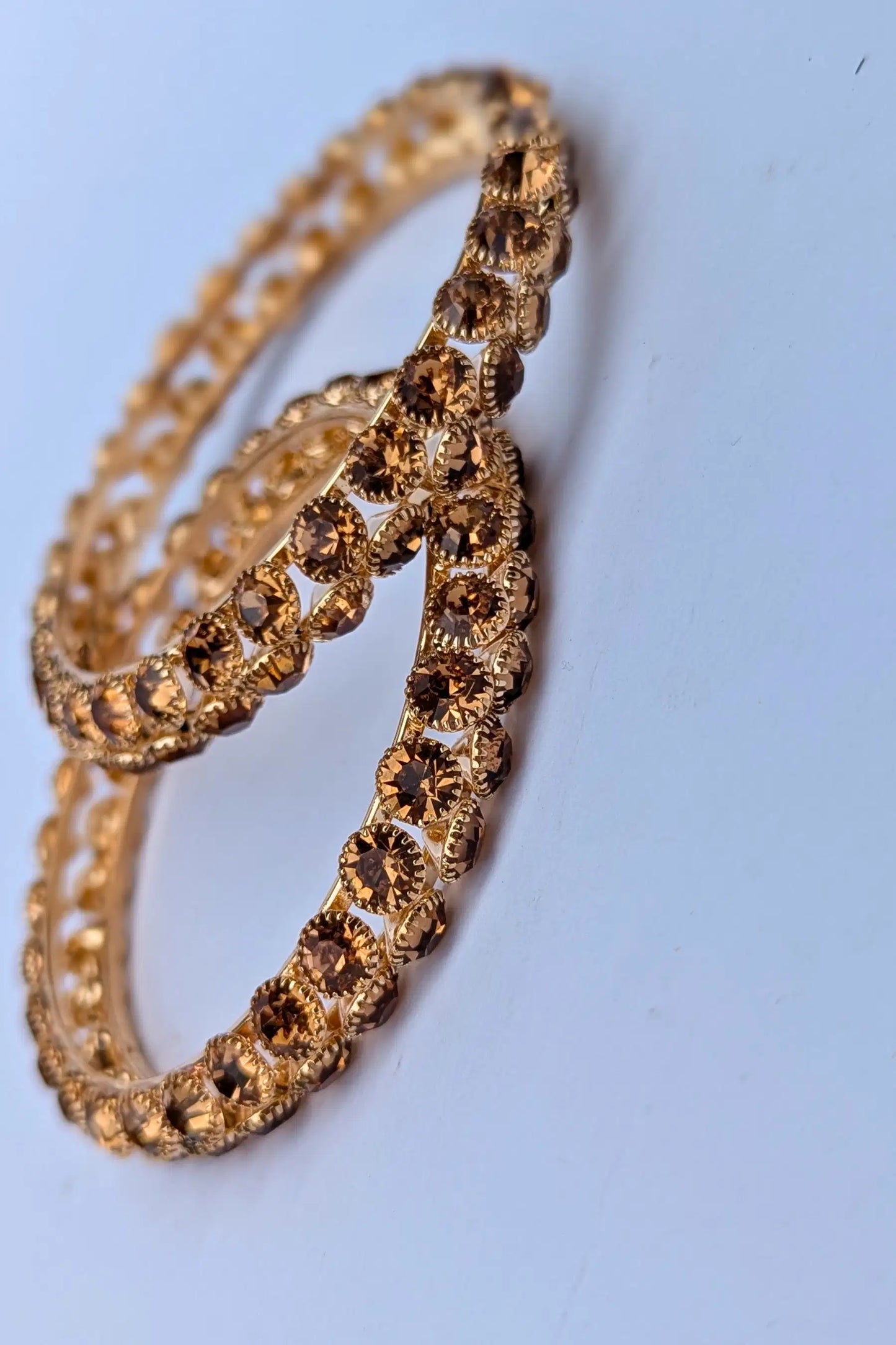 Gold bracelet with clear stones on a light blue background