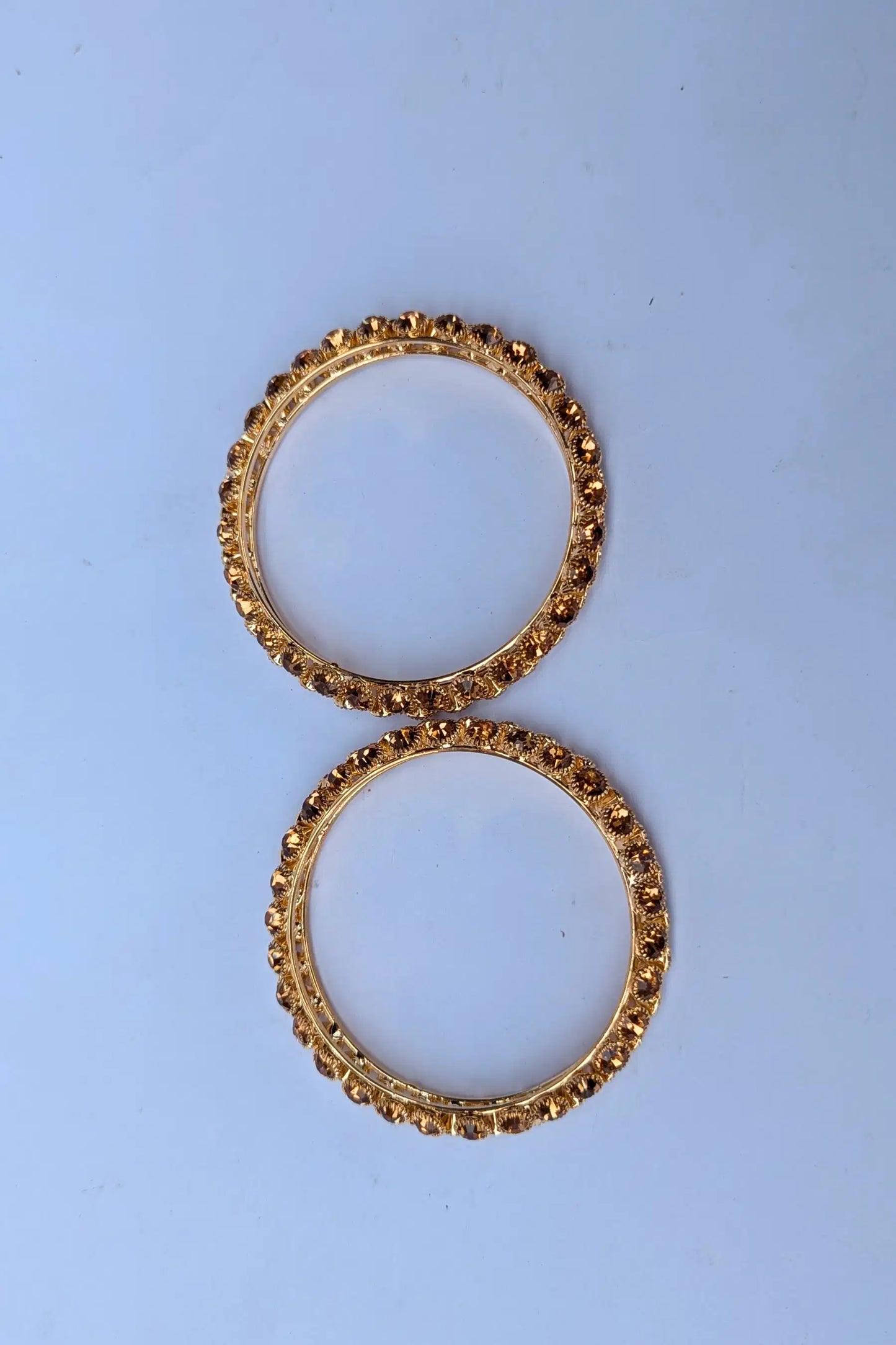 Two gold hoop earrings on a light blue background