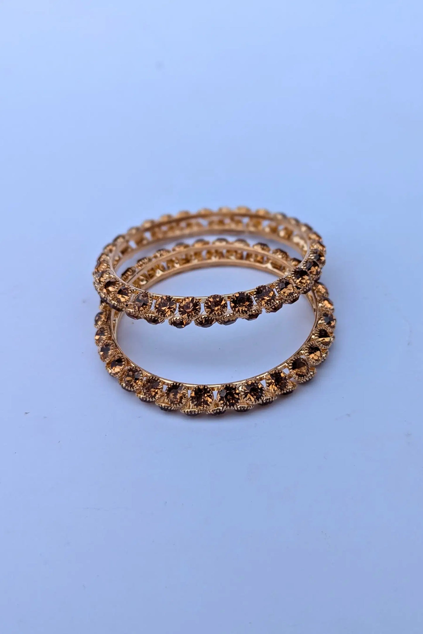 Two gold rings with embedded stones on a light blue background