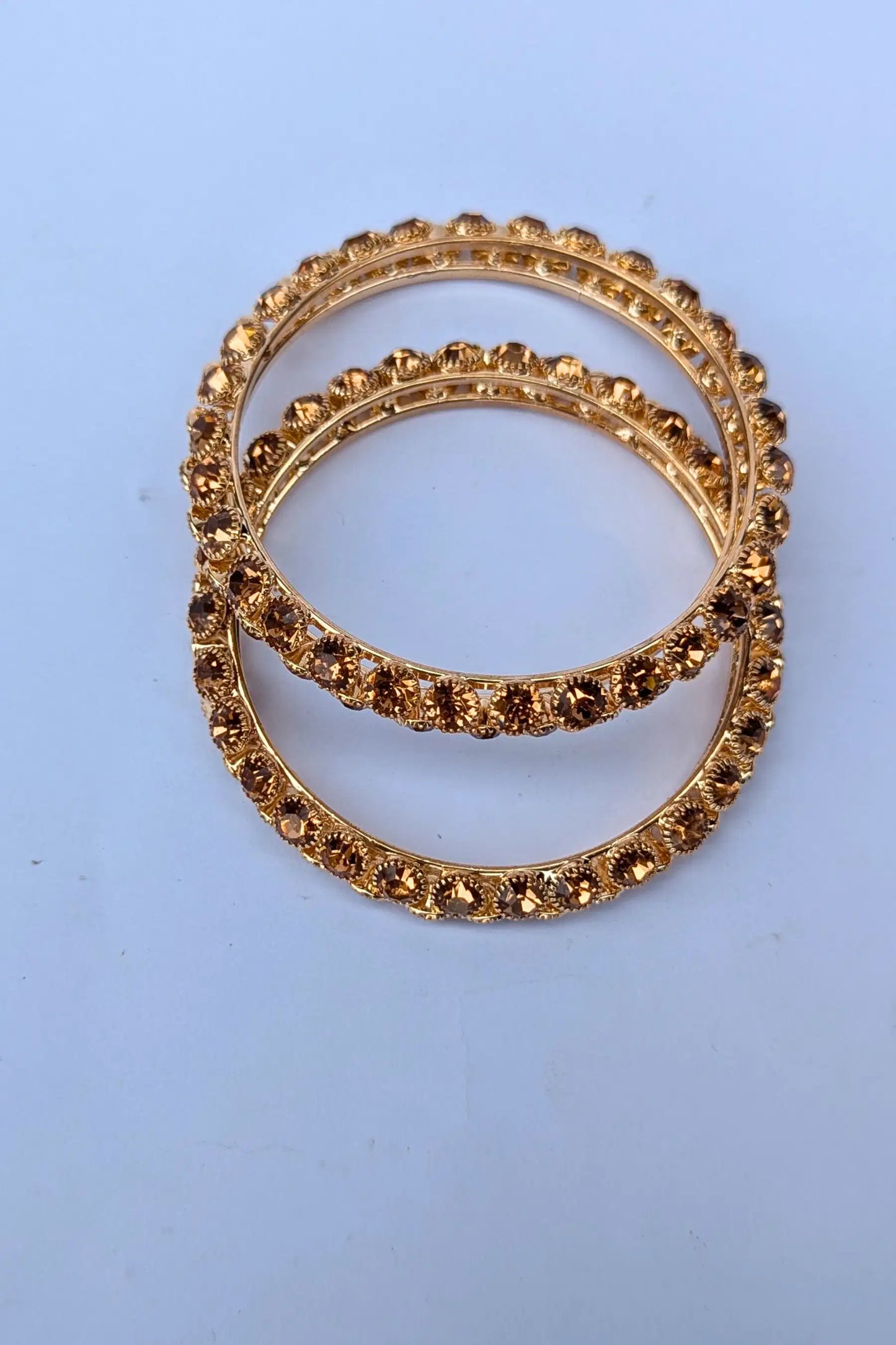 Two golden rings with embedded stones on a light blue background