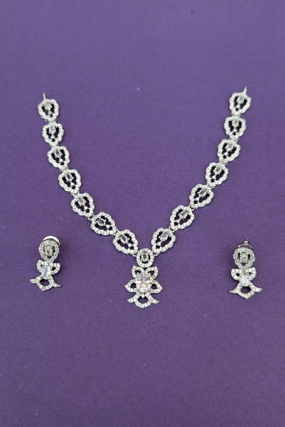 Silver necklace and earrings set on a purple background