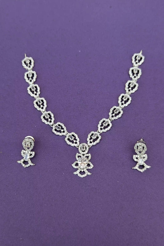 Silver necklace and earrings set on a purple background