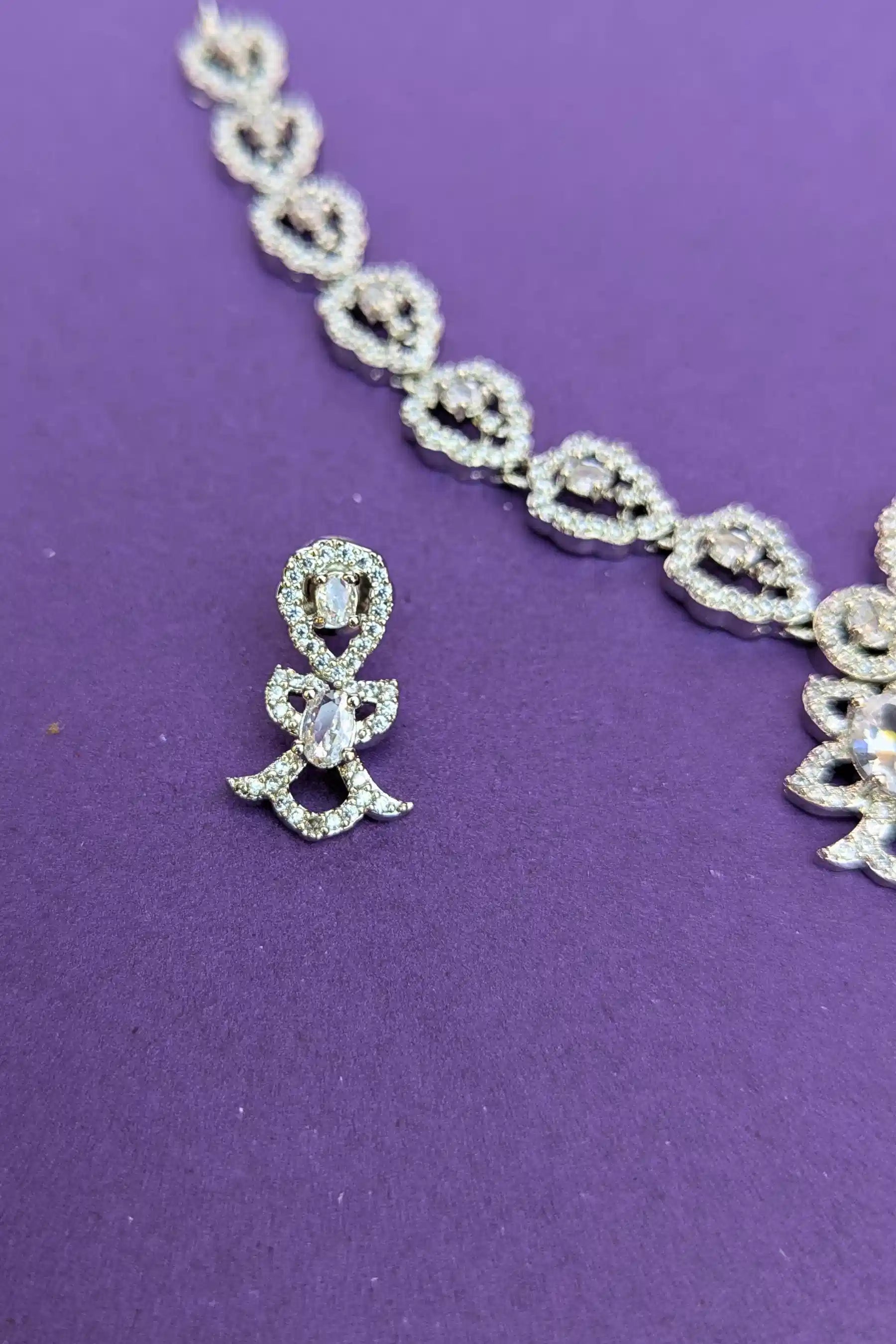 Silver necklace and earrings on a purple background
