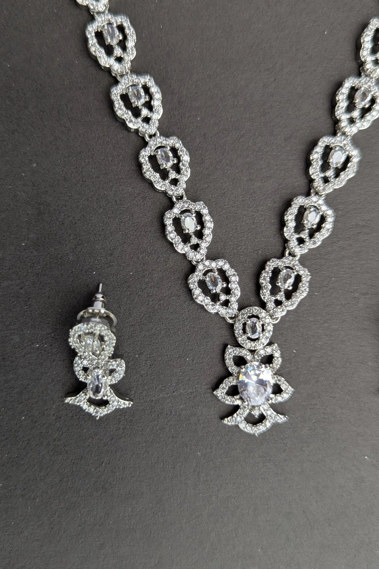 Silver necklace and earrings on a dark background