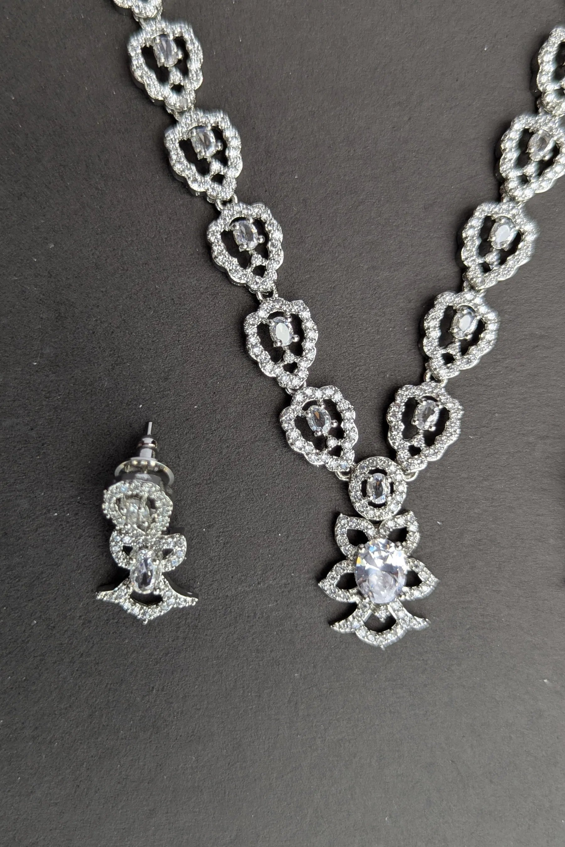 Silver necklace and earrings on a dark background
