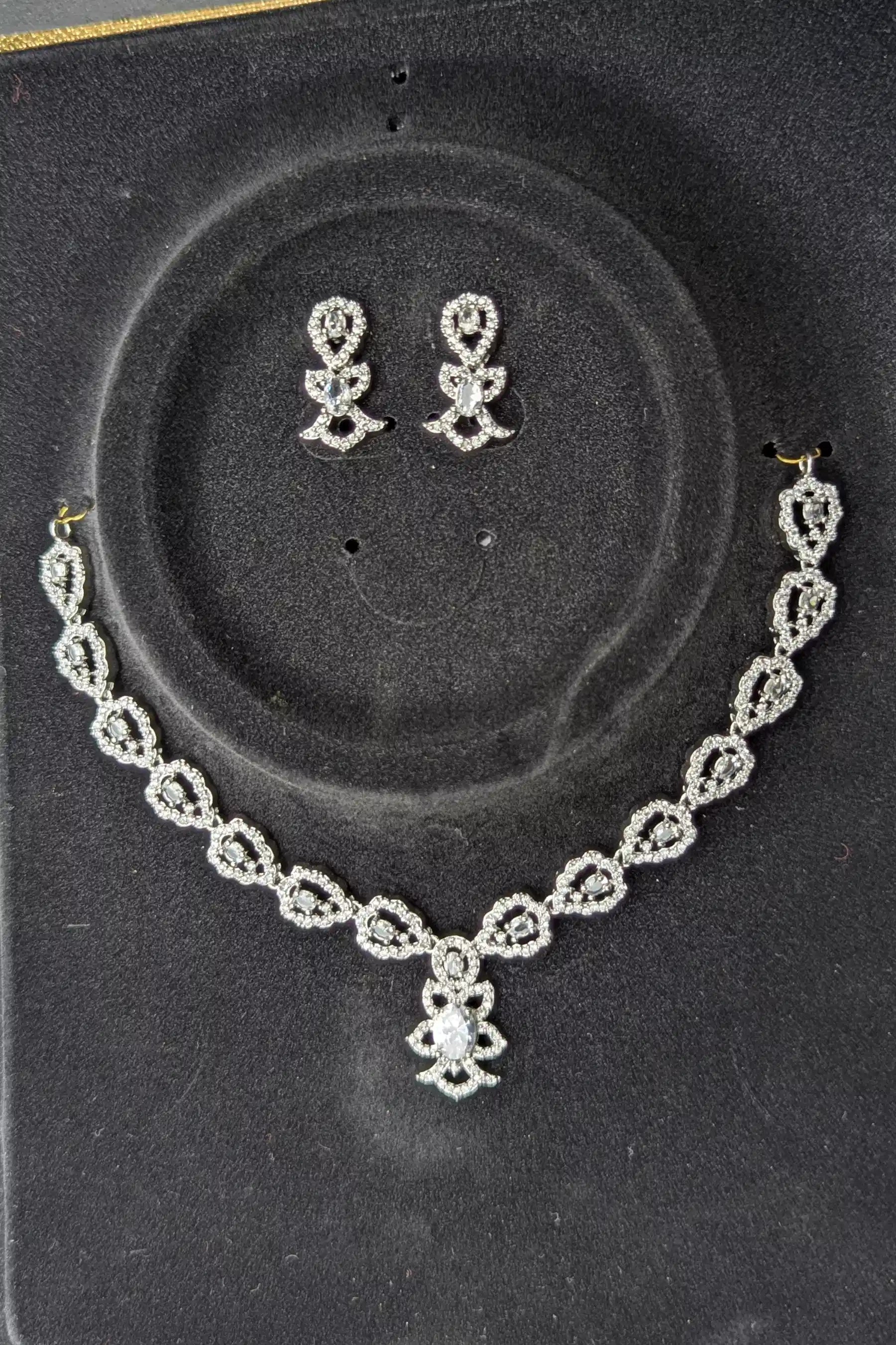Silver necklace and earrings set on a black display box