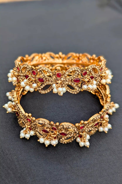 Golden bracelet with red stones and pearls on a dark background