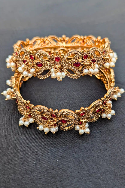 Golden bracelet with red stones and pearls on a dark background