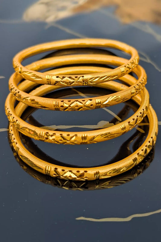 Stack of gold bangles on a reflective surface