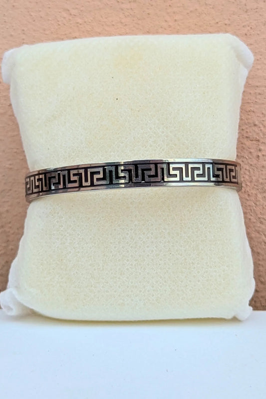 Bracelet with a decorative pattern on a white cushion against a beige background
