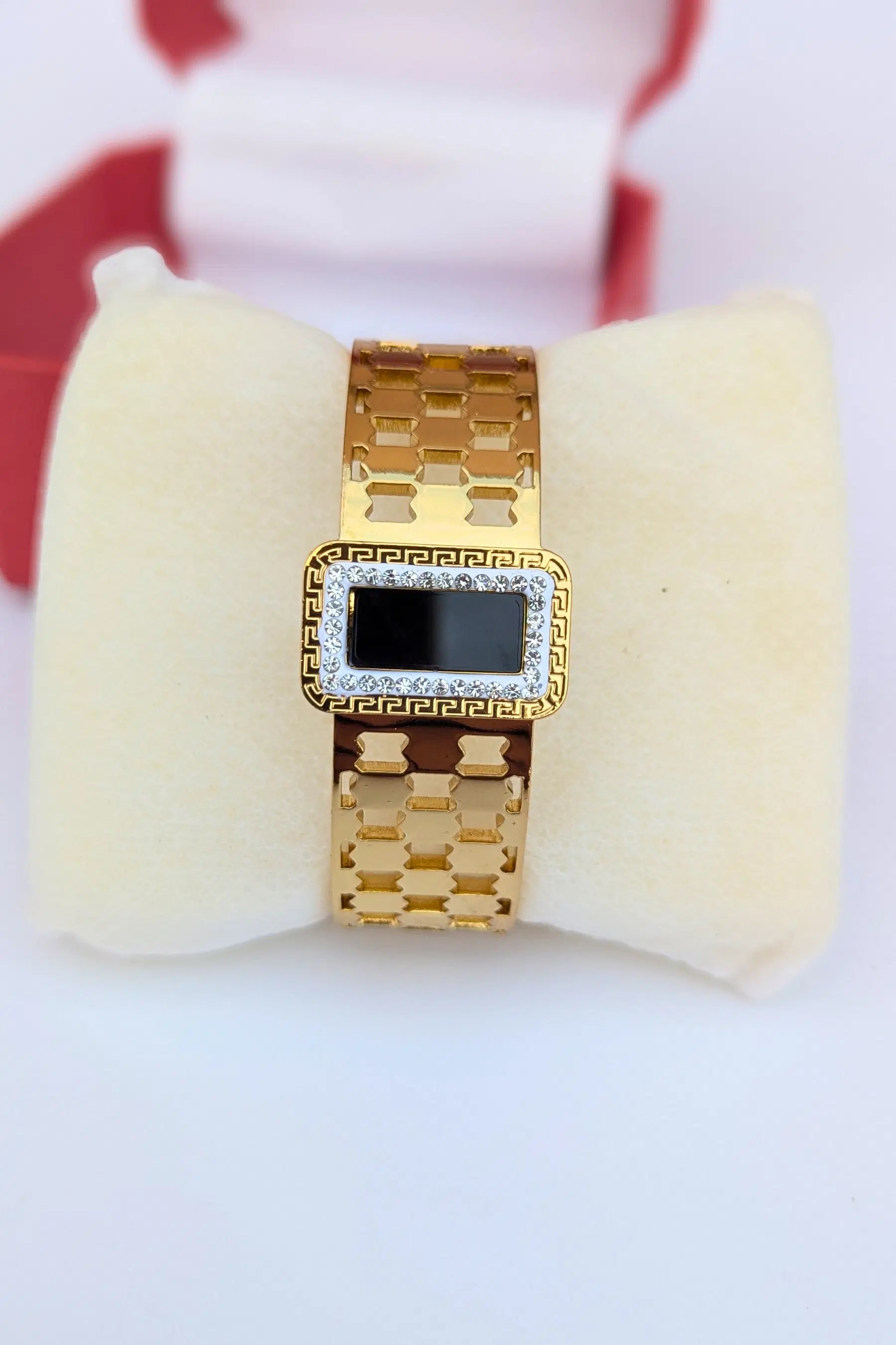 Gold bracelet with a square gemstone on a white cushion